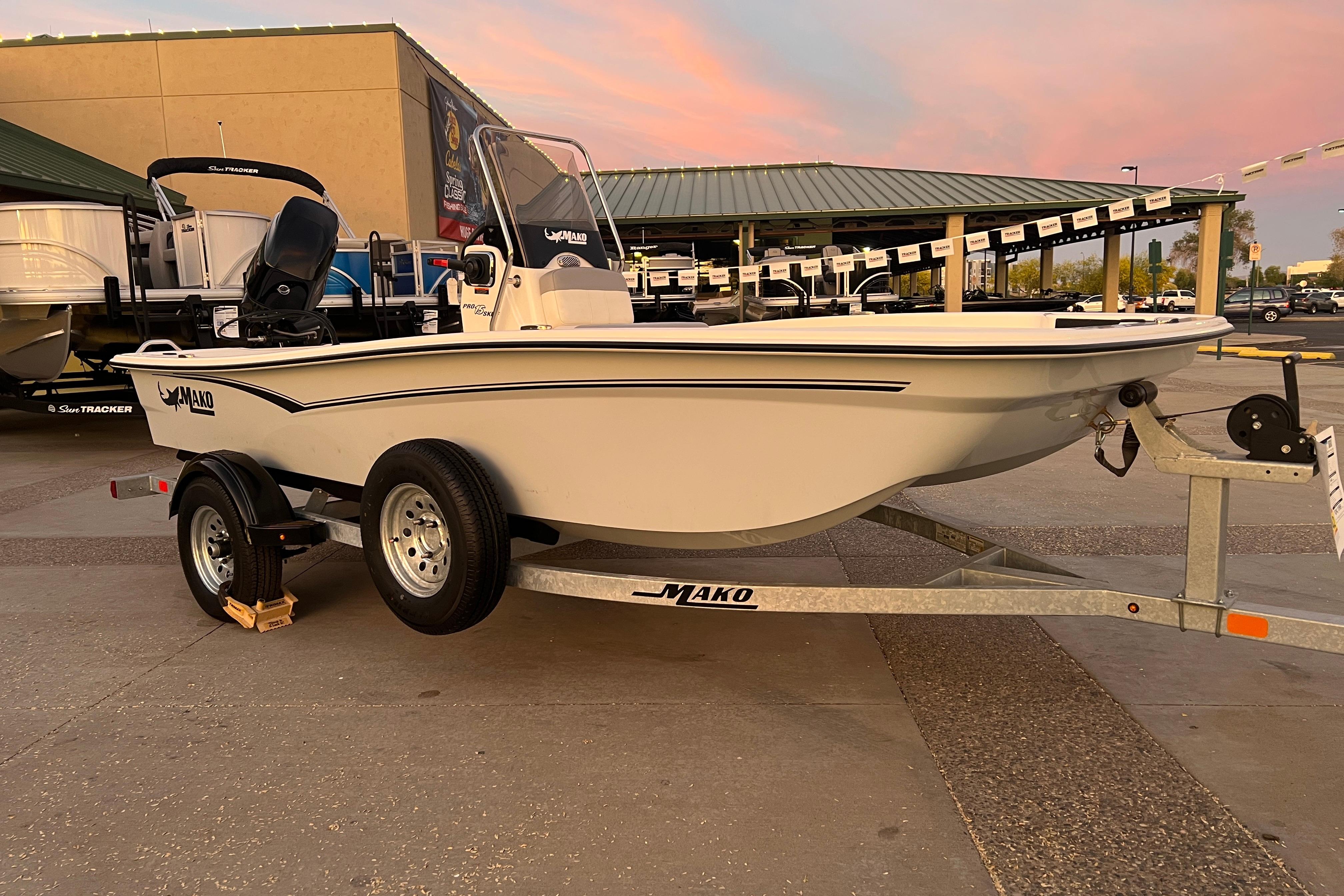 2025 Mako Pro Skiff 15 CC boat on trailer at dealership, sunset background.