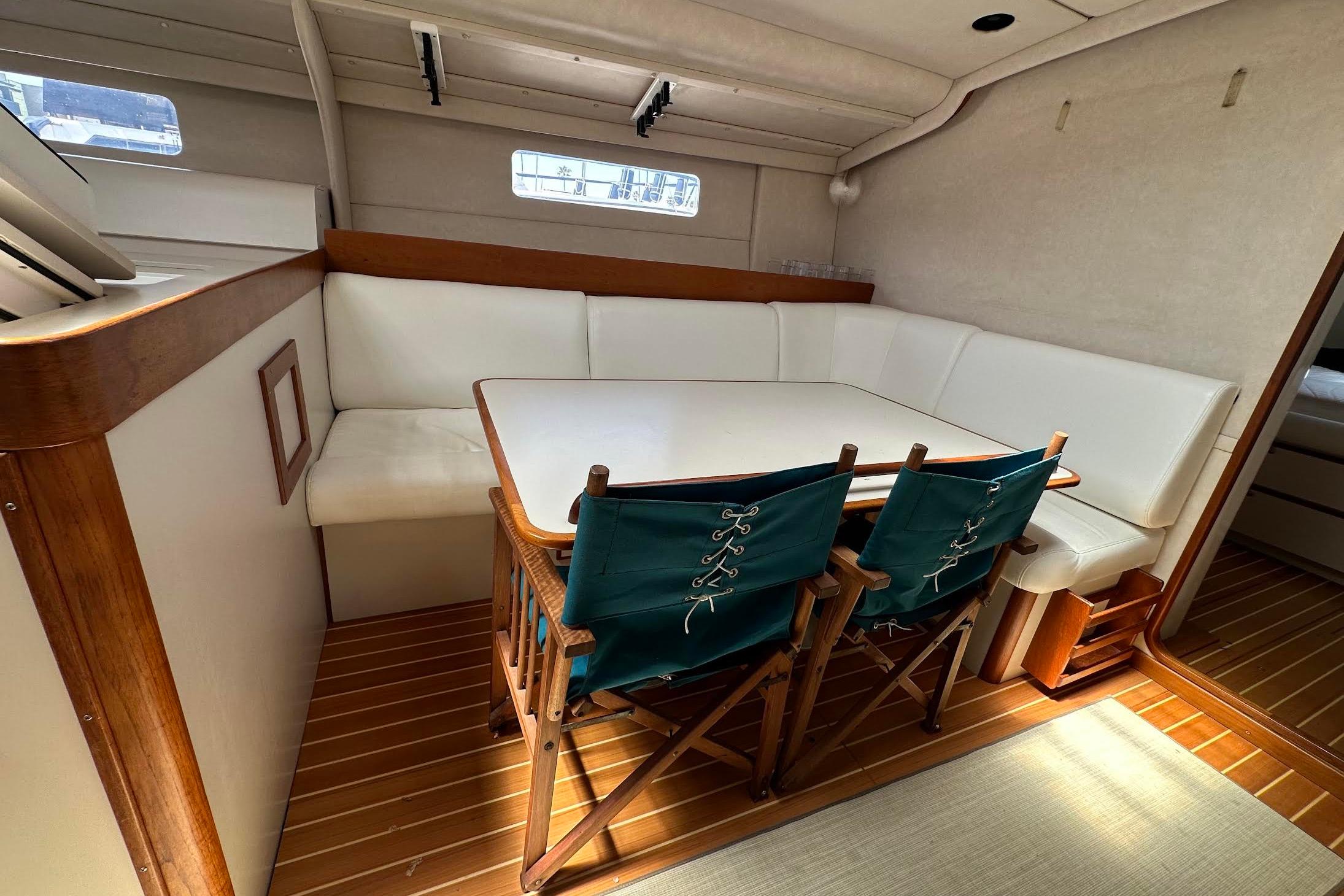 Interior of a 1995 Sundeer 56 yacht with a cozy dining area and wooden flooring.