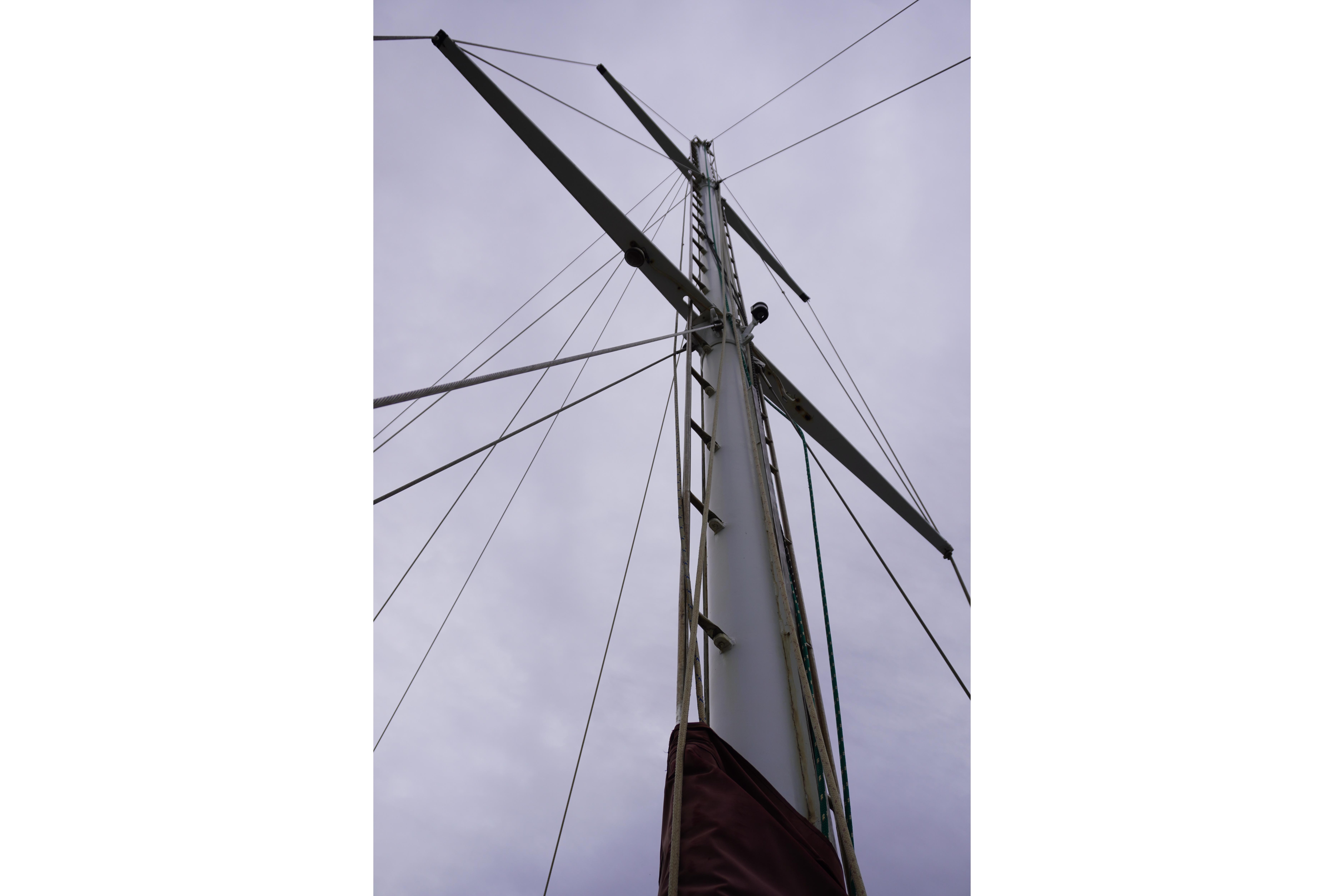 Mast of 1976 Manila Shipbuilders sailboat against cloudy sky.