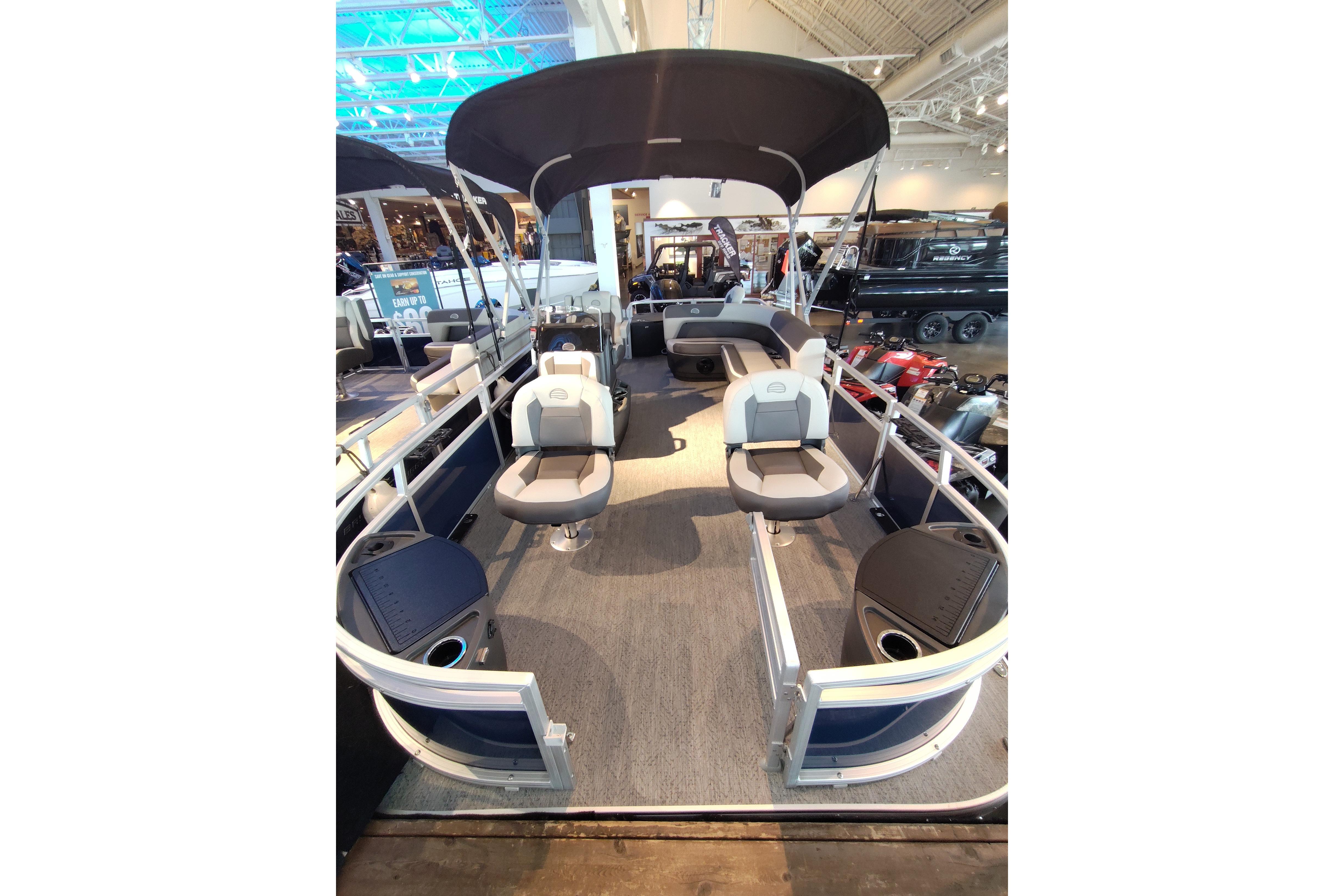 2026 Sun Tracker Bass Buggy 18 DLX pontoon boat with canopy and seating, displayed indoors.