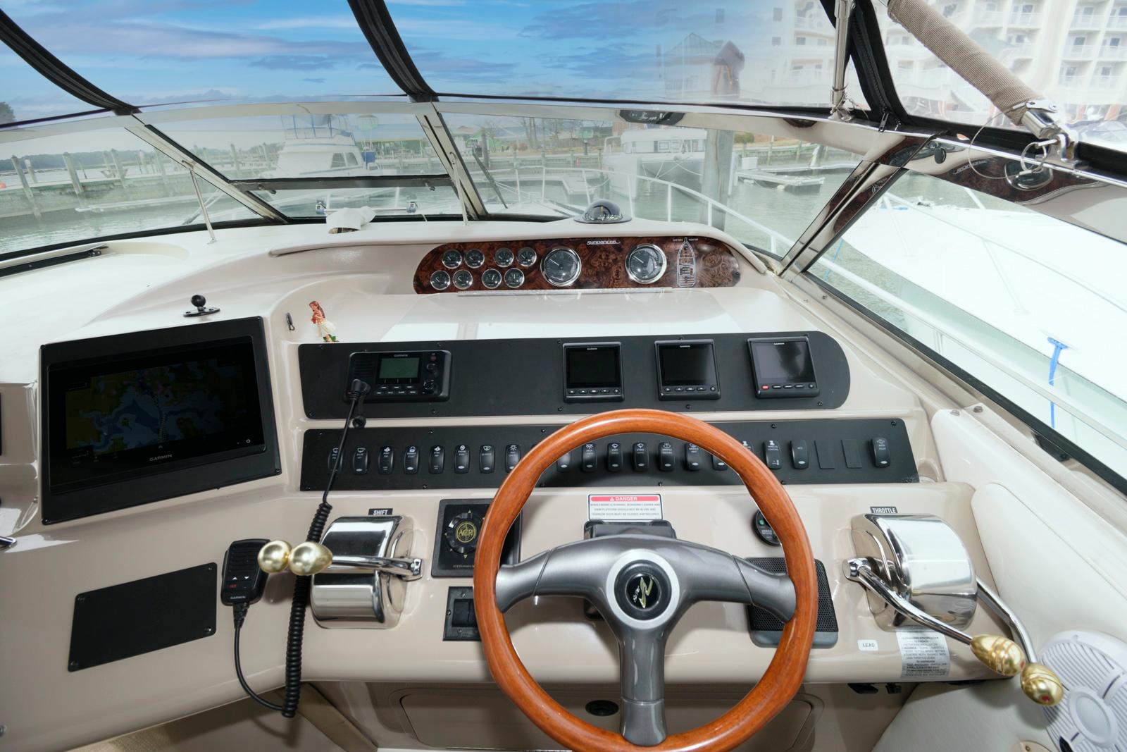 1998 Sea Ray 450 Sundancer helm with wood steering wheel and modern navigation controls.