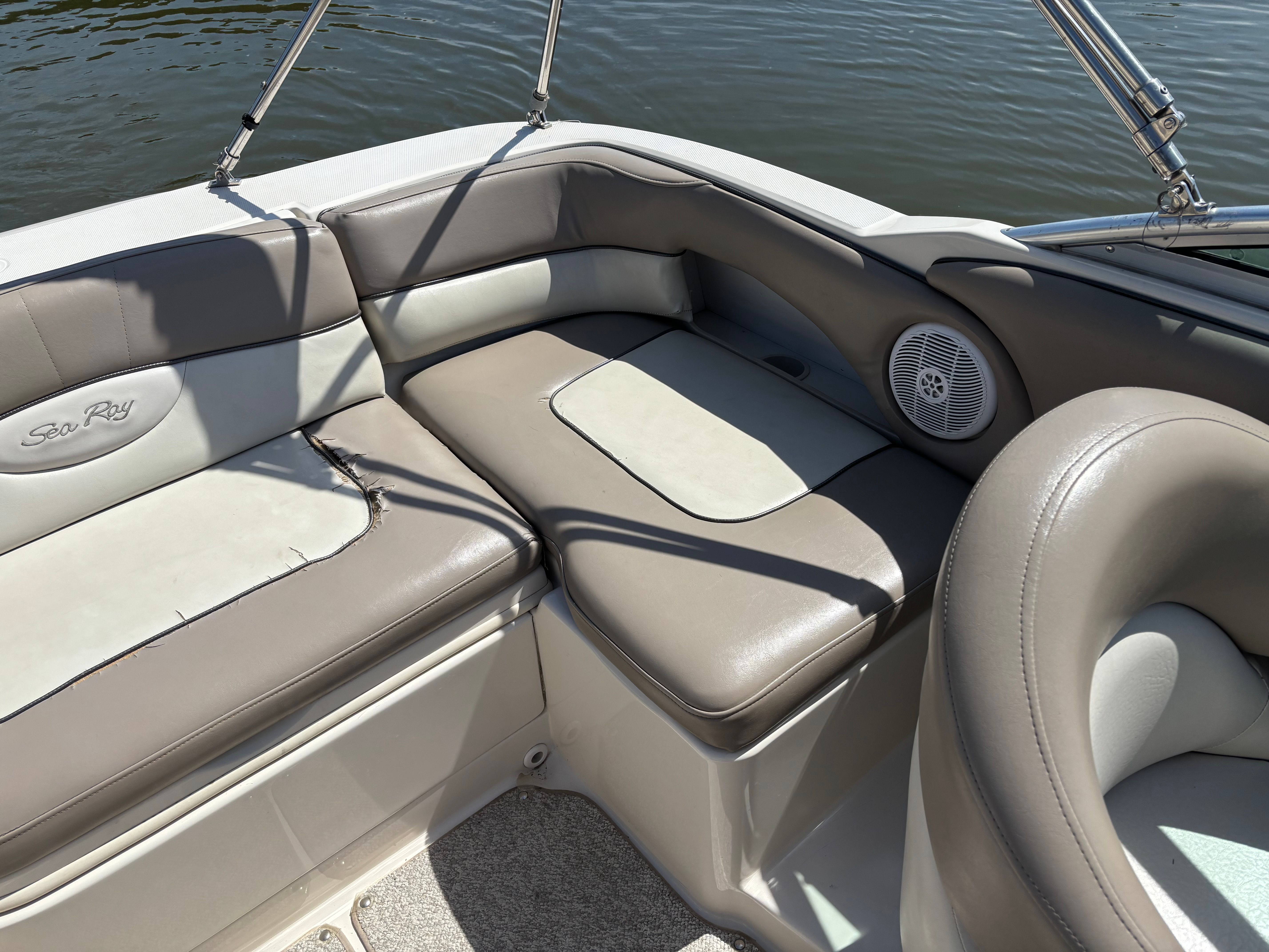 Interior of a Sea Ray 220 Sundeck boat with gray upholstery and speaker.