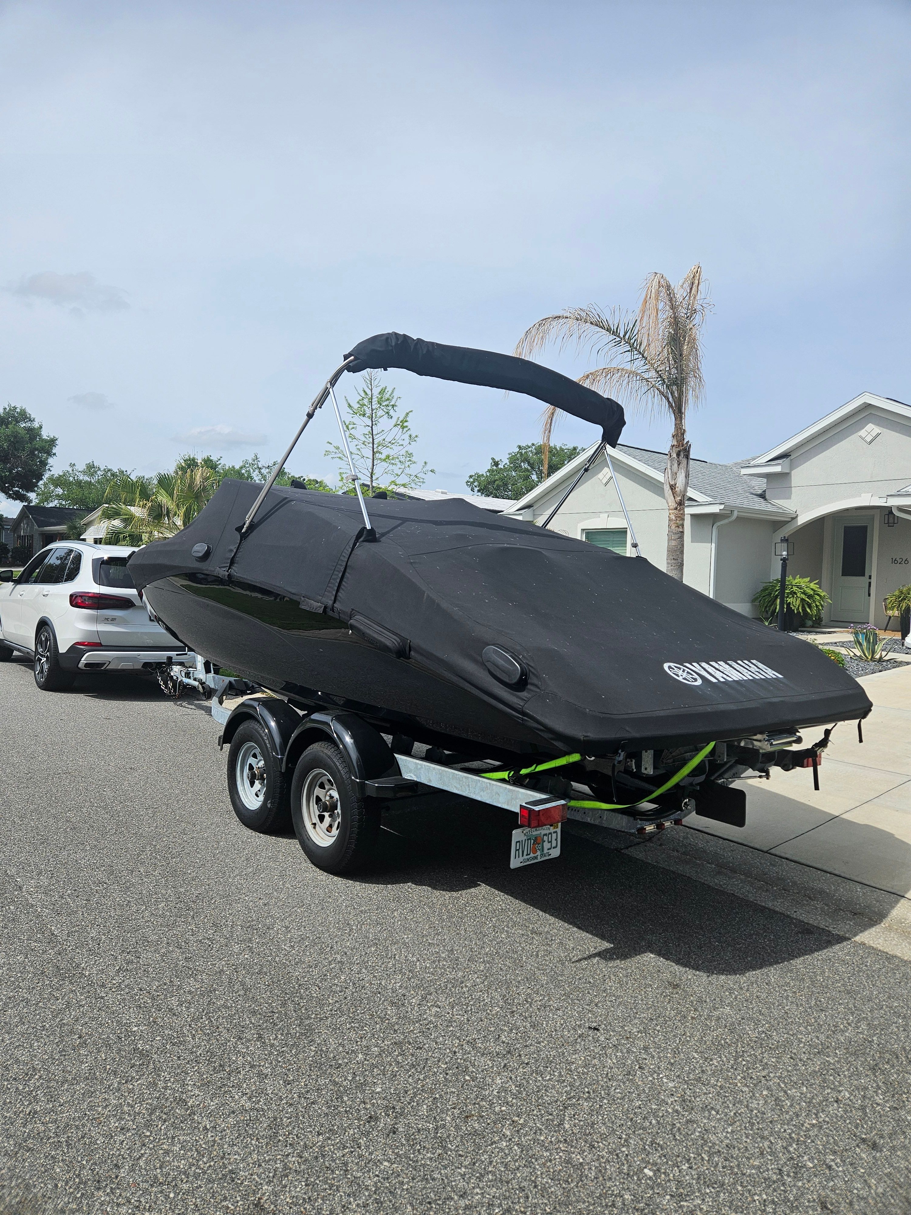 2022 Yamaha SX210 boat on trailer, covered, parked on street.