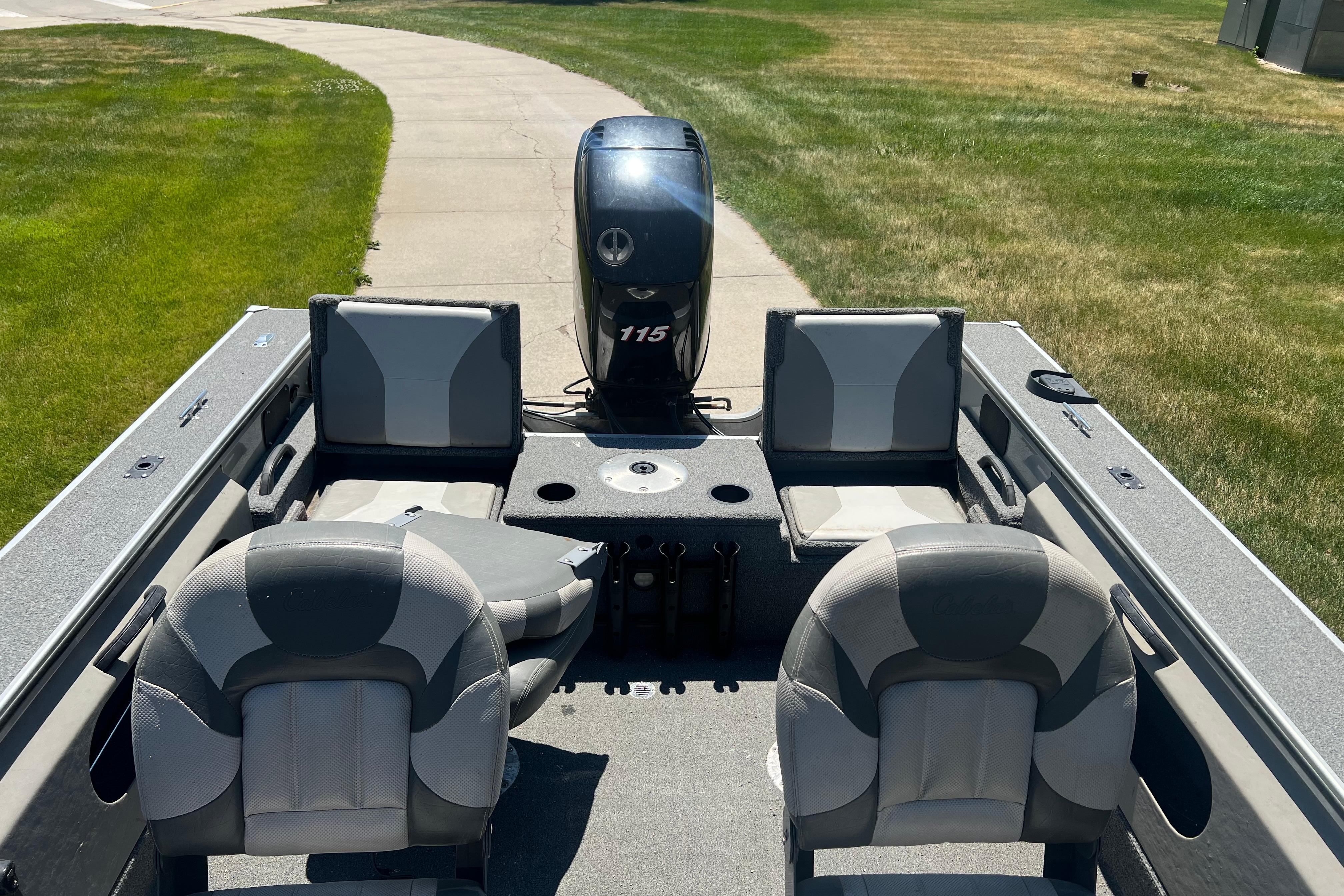 2010 Alumacraft Dominator 165 Sport boat interior with seating and motor, parked on grass.