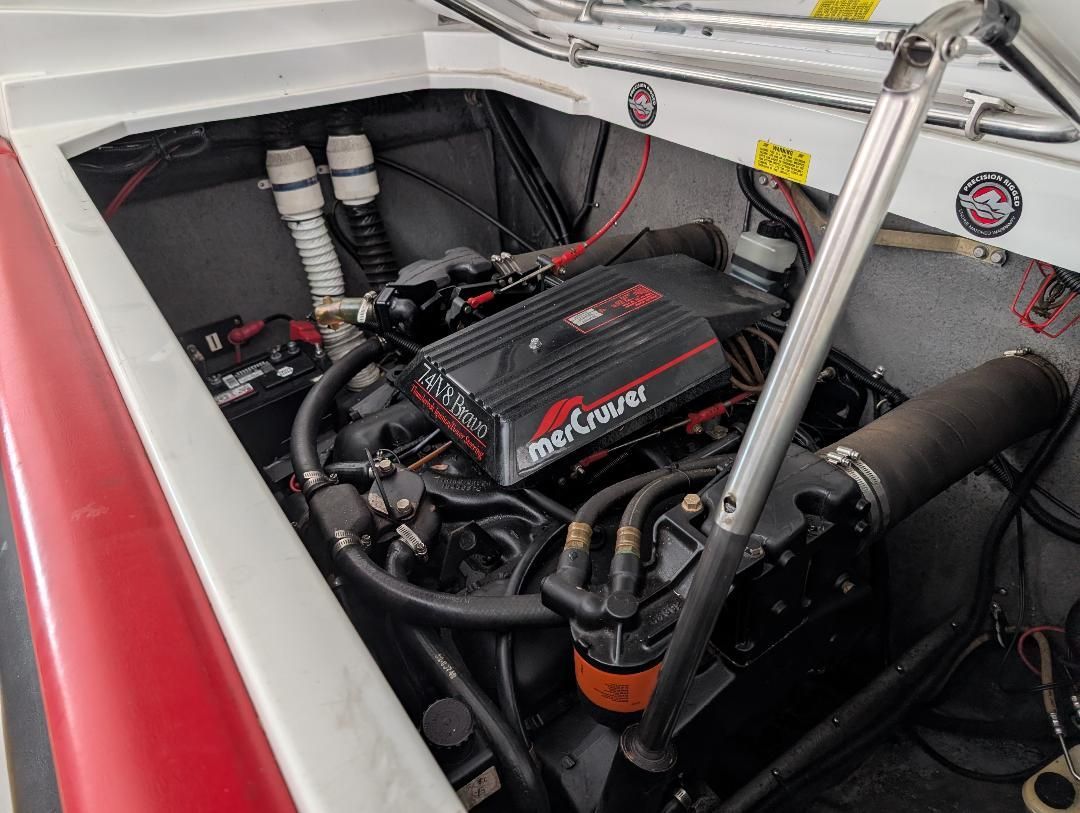 The engine compartment of a 1989 Formula F223LS boat features a MerCruiser engine with hoses and cables.