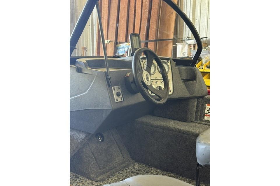 Interior view of 2026 Tracker Pro Guide V-16 WT boat, featuring steering wheel and dashboard controls.