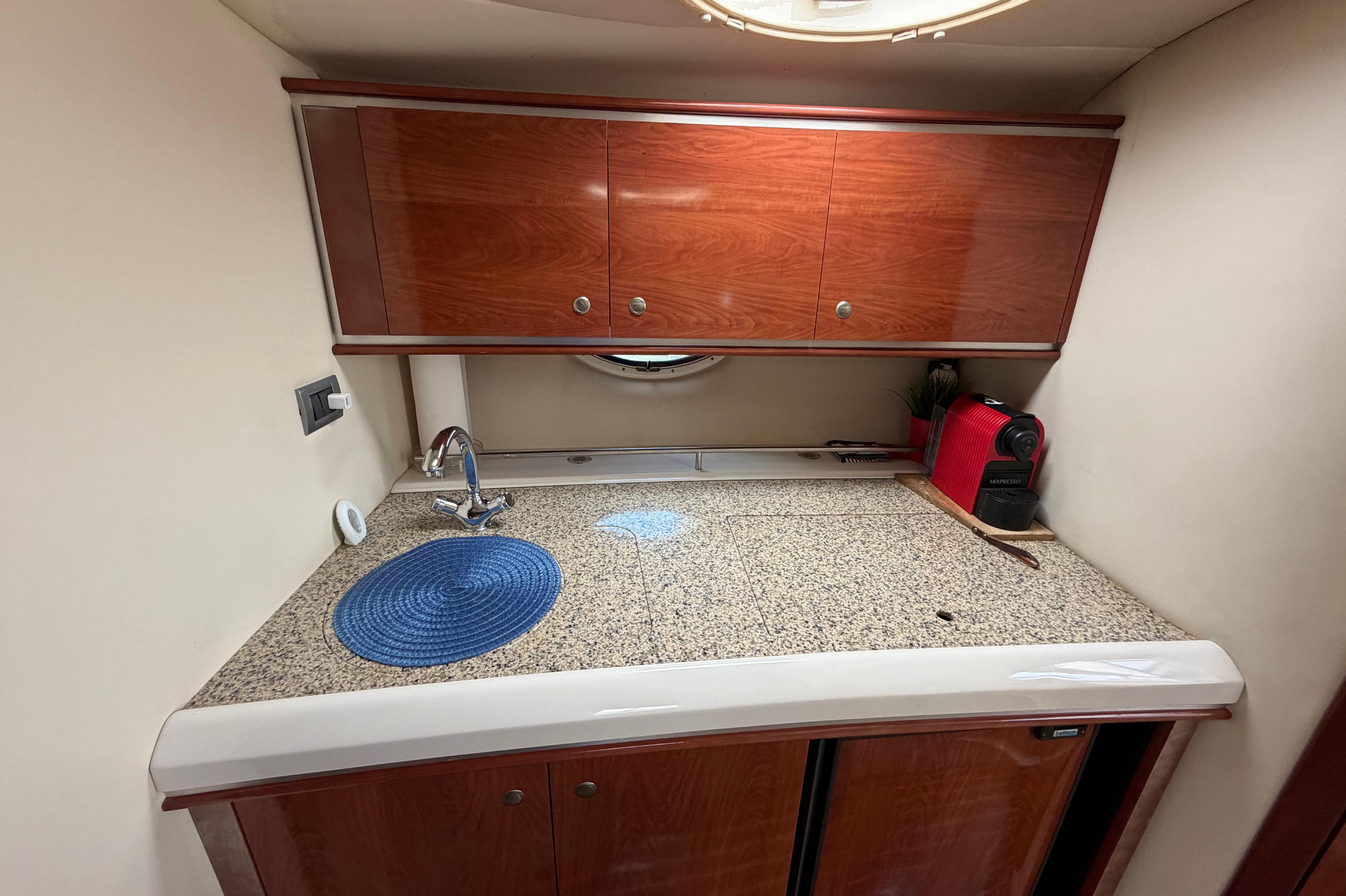 Compact kitchen area in a 2007 Monterey 350 Sport Yacht with wooden cabinets and granite countertop.