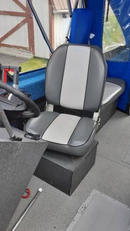 A gray and black seat in a boat with blue interior.