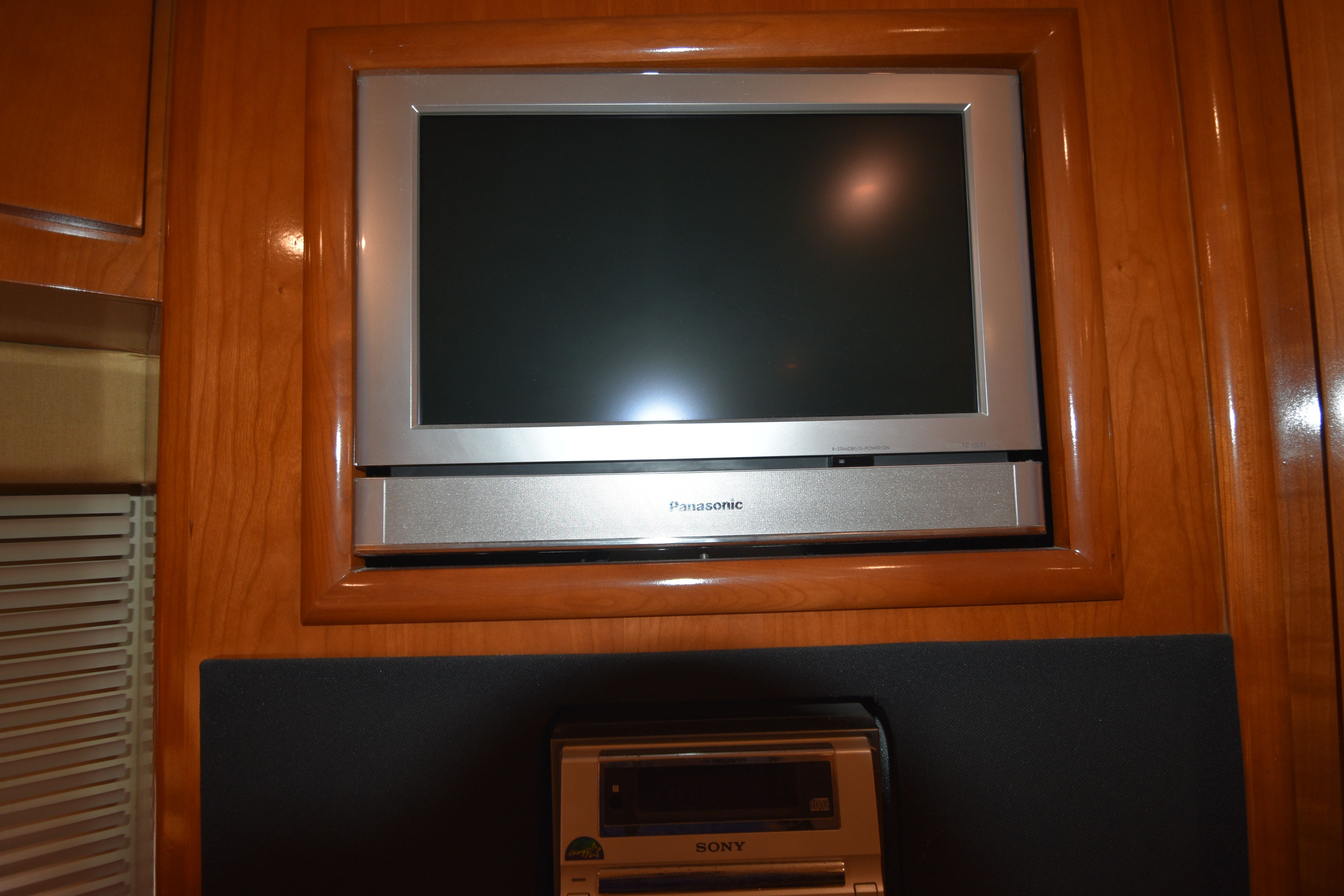 A flat-screen TV is mounted in a wooden wall, with a Sony device below it.