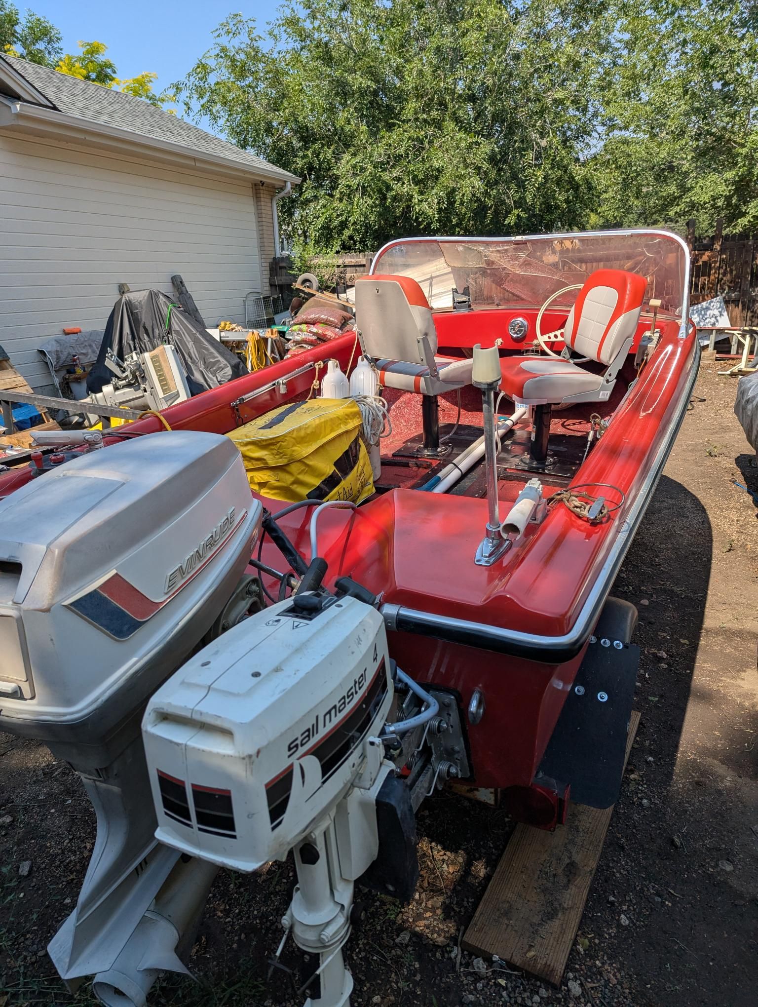 A red 1972 14-foot Swiss Craft runabout with outboard motor, parked outdoors.