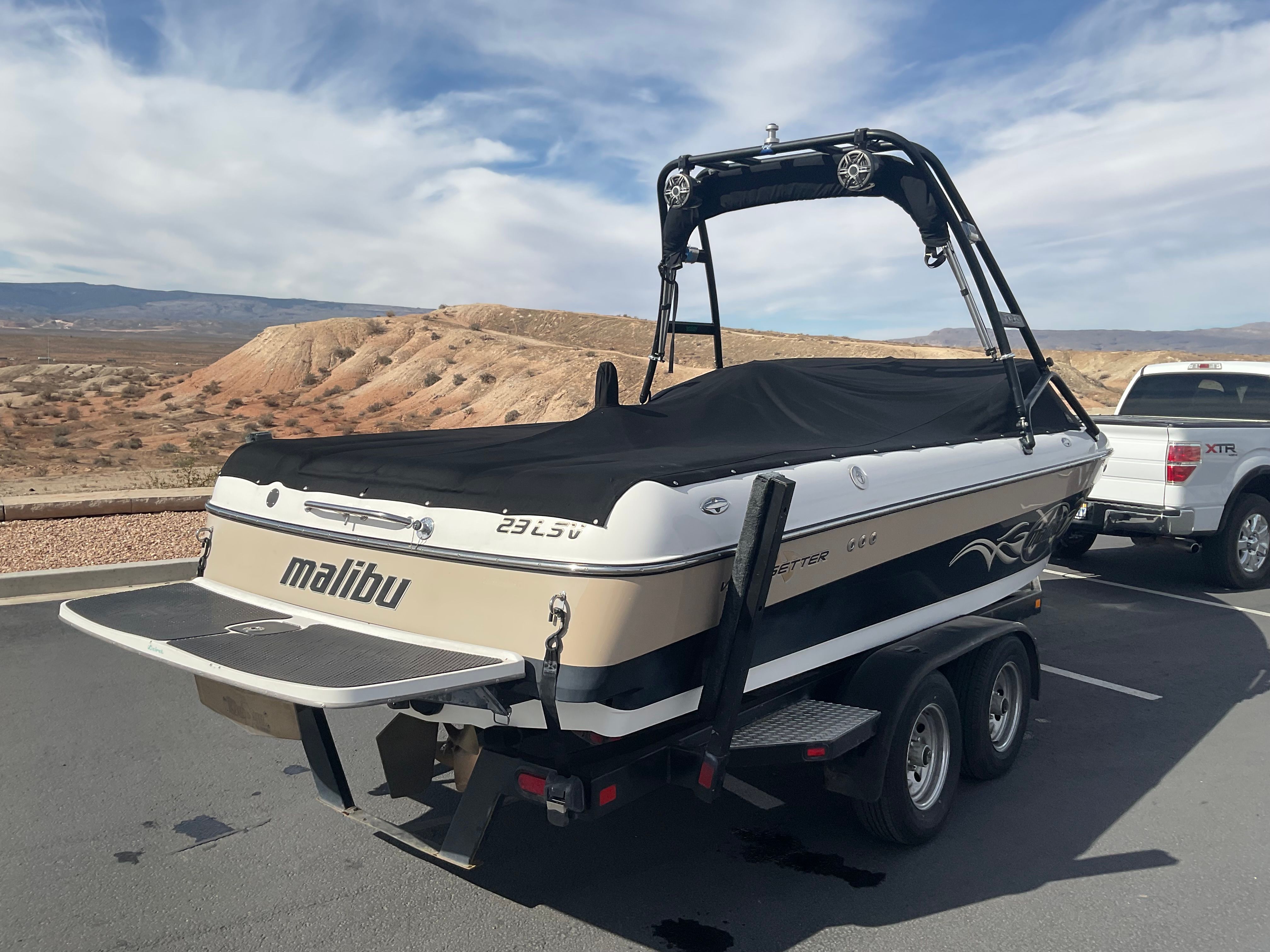 A 2003 Malibu Wakesetter 23 LSV on a trailer in a dry, desert landscape.
