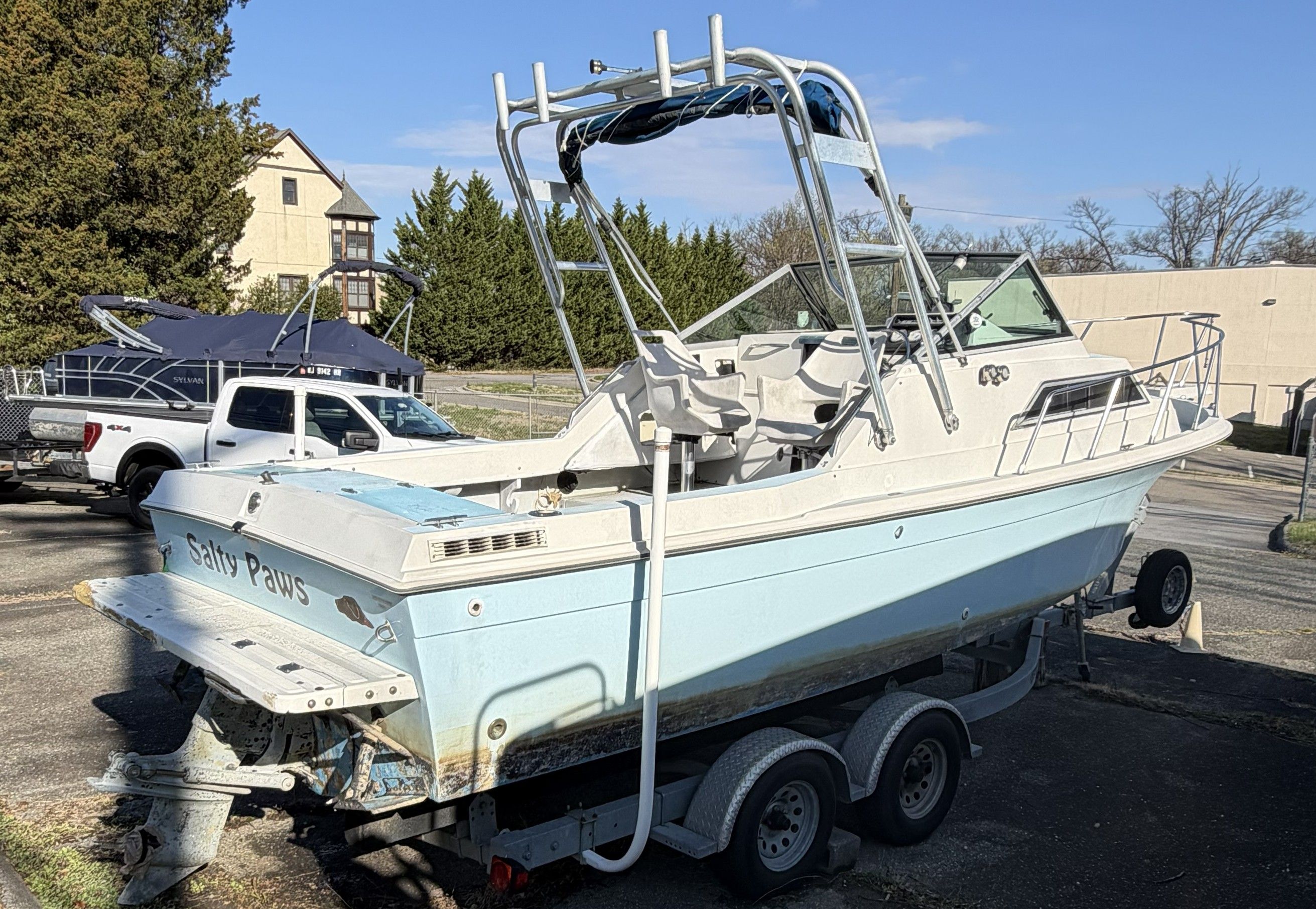A 1989 Wellcraft 250 Sportsman on a trailer, featuring a blue hull and T-tops.