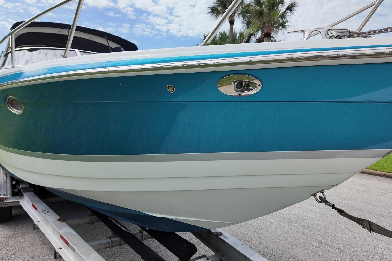 2007 Formula 330 Sun Sport boat on trailer, blue hull, palm trees in background.