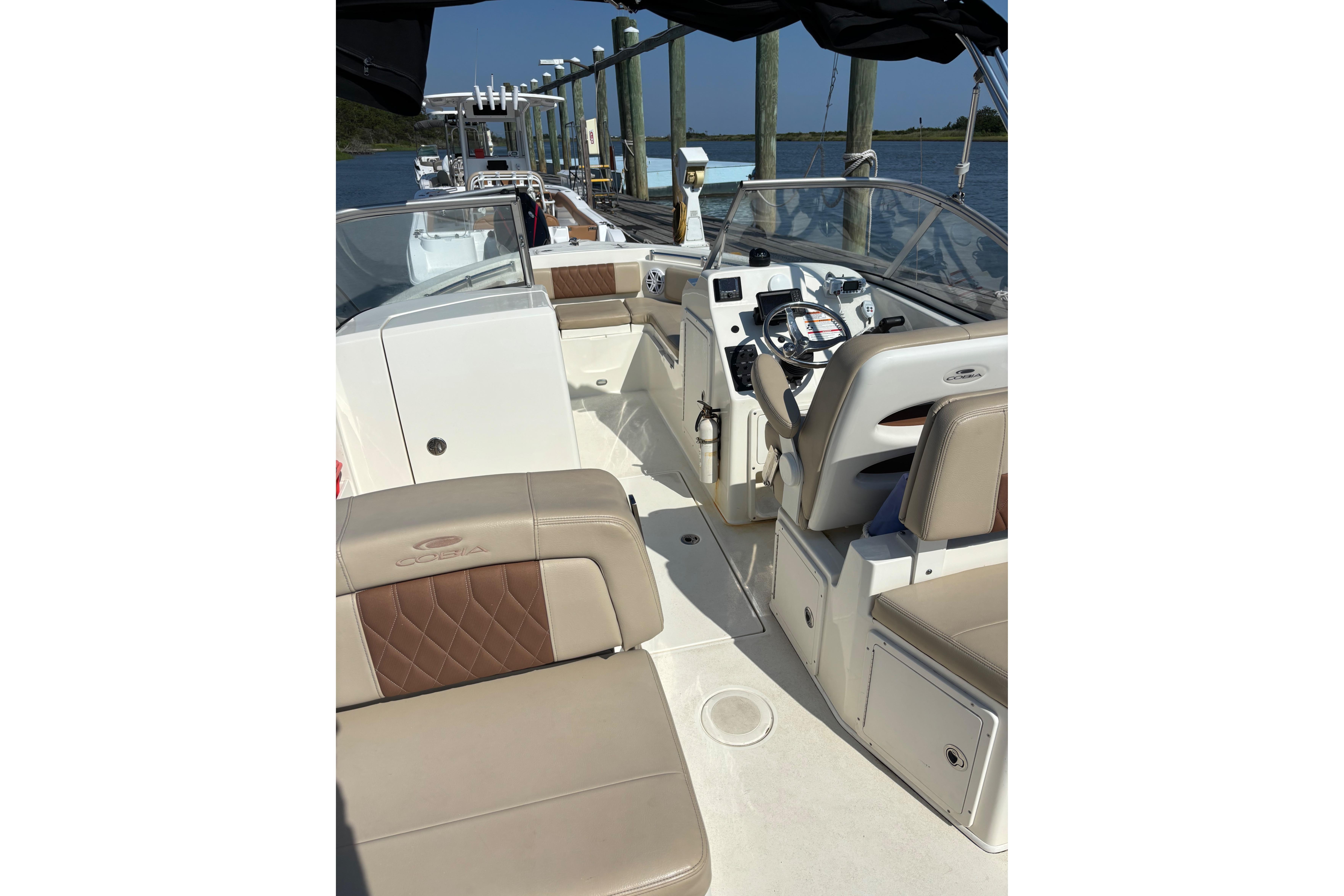 2024 Cobia 220 Dual Console boat interior with beige seating and steering console.