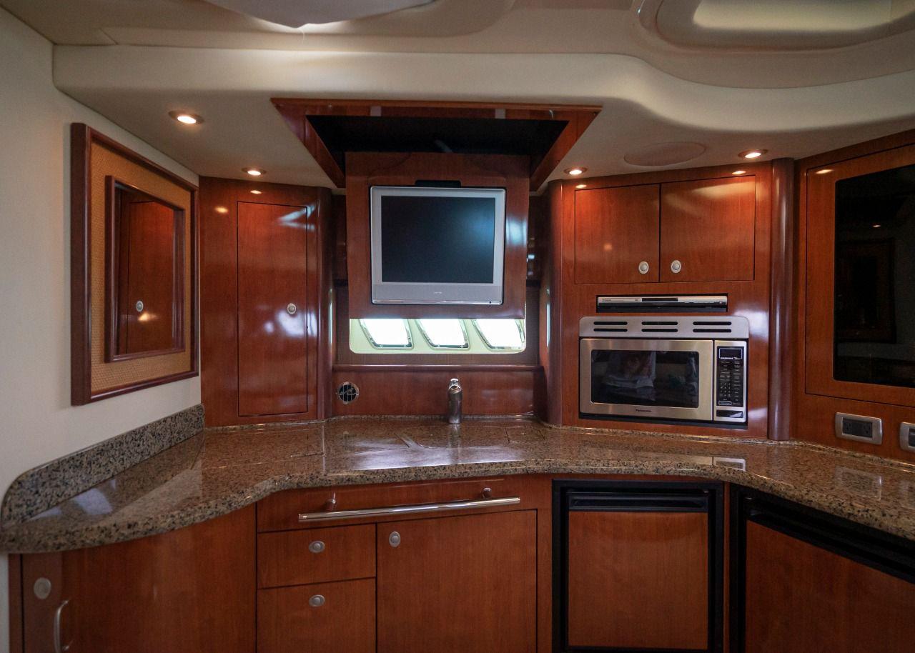 Luxurious kitchen interior of 2006 Sea Ray 440 Sundancer yacht with wood cabinetry and modern appliances.