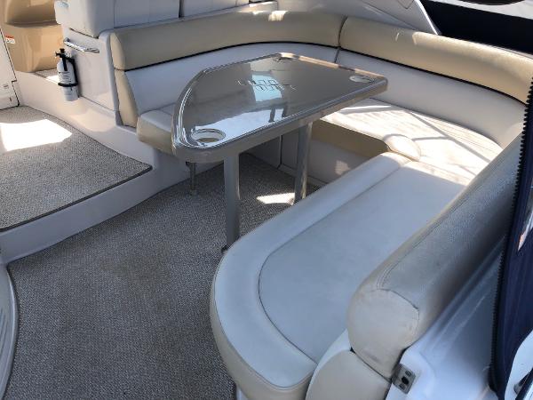 Interior of a 2008 Four Winns V338 with beige upholstered seating and a table.