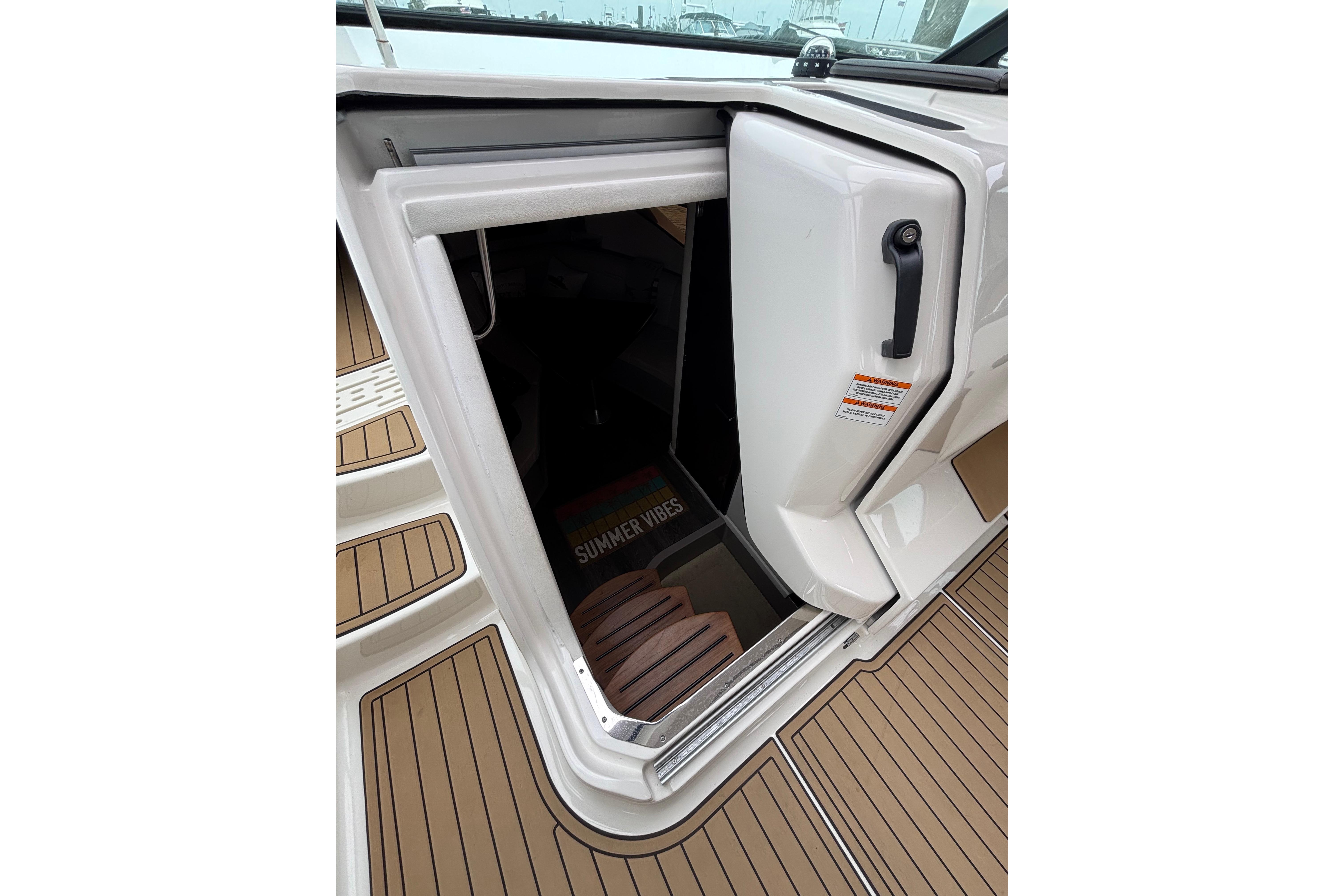 2021 Sea Ray Sundancer 320 Outboard cabin entrance with teak flooring and "Summer Vibes" mat.
