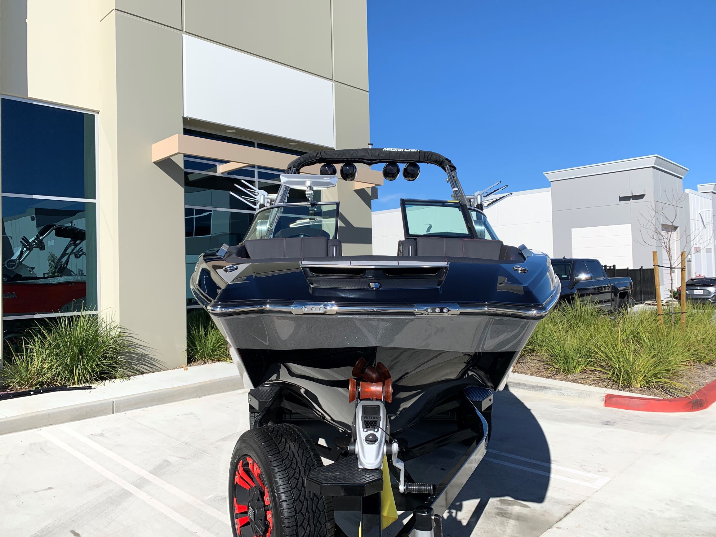 A 2020 MasterCraft X24 boat on a trailer in front of a modern building.