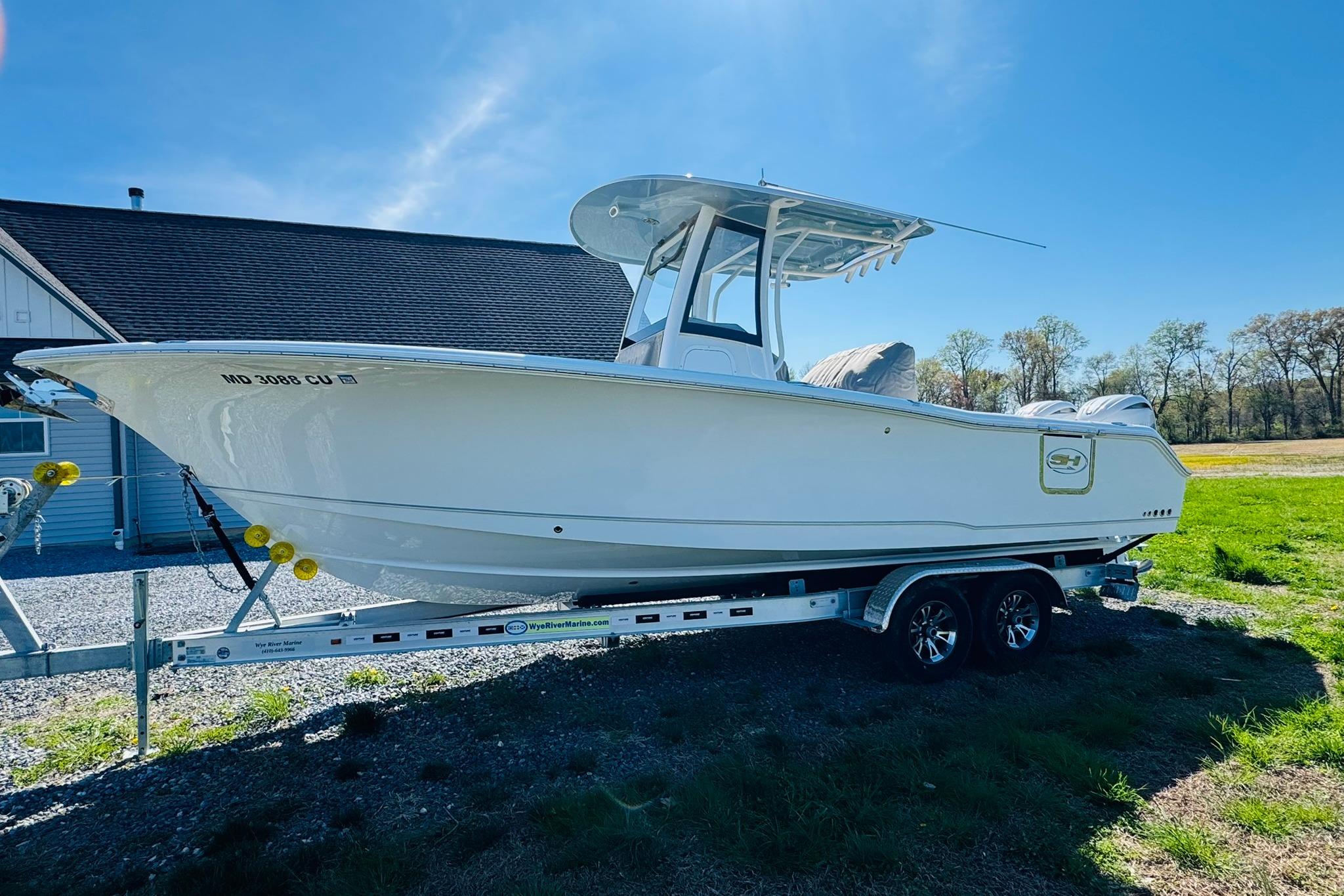 2024 Sea Hunt Gamefish 25 boat on trailer, parked outdoors under clear blue sky.