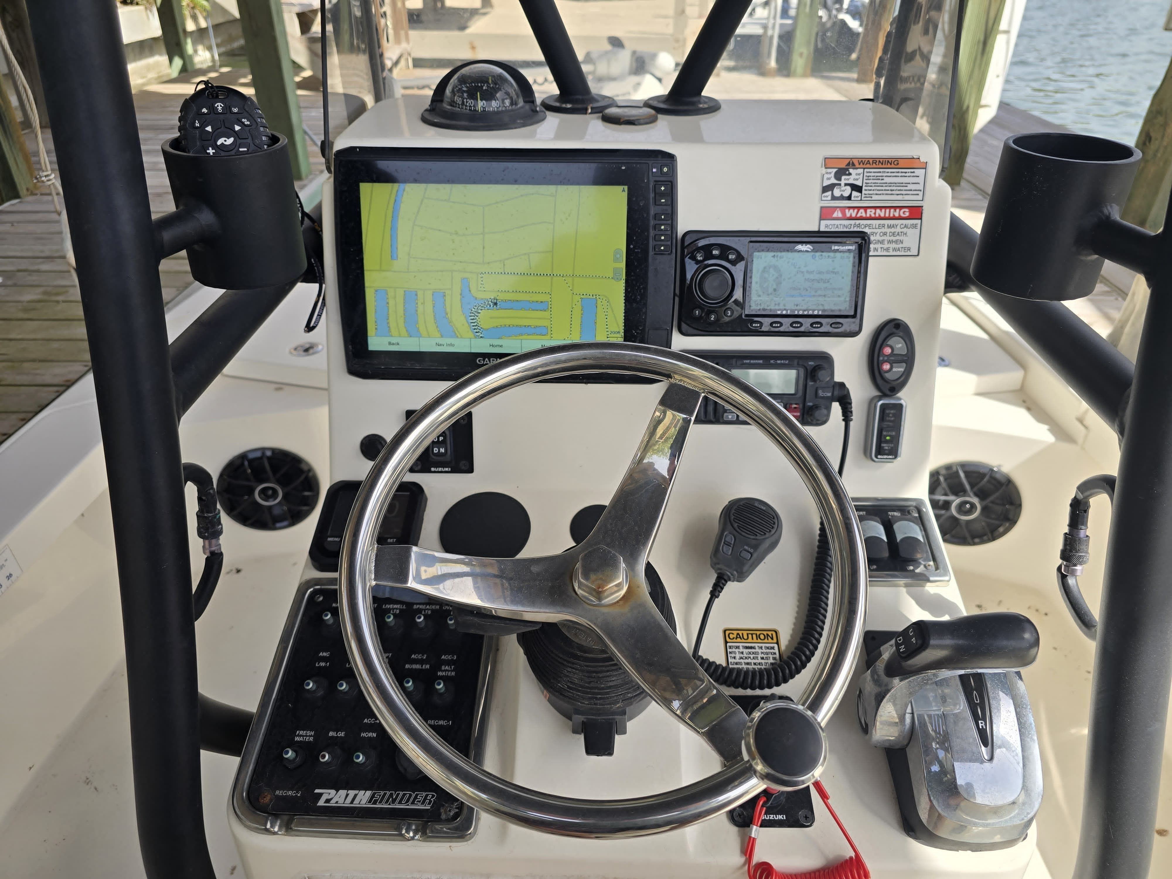 The cockpit of a boat with steering wheel, navigation system, and controls.