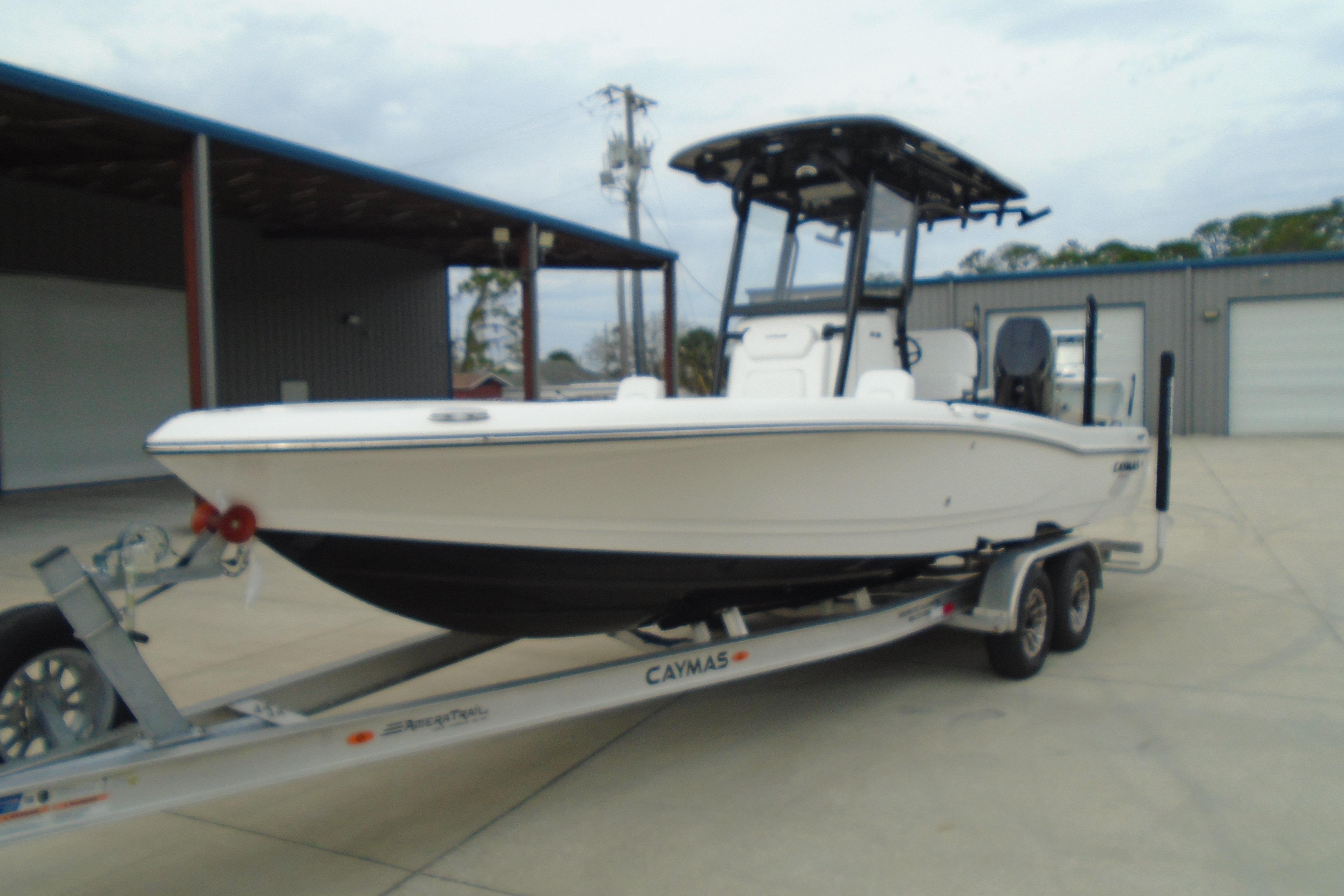 2026 Caymas 26 HB boat on trailer, parked outdoors near industrial buildings.