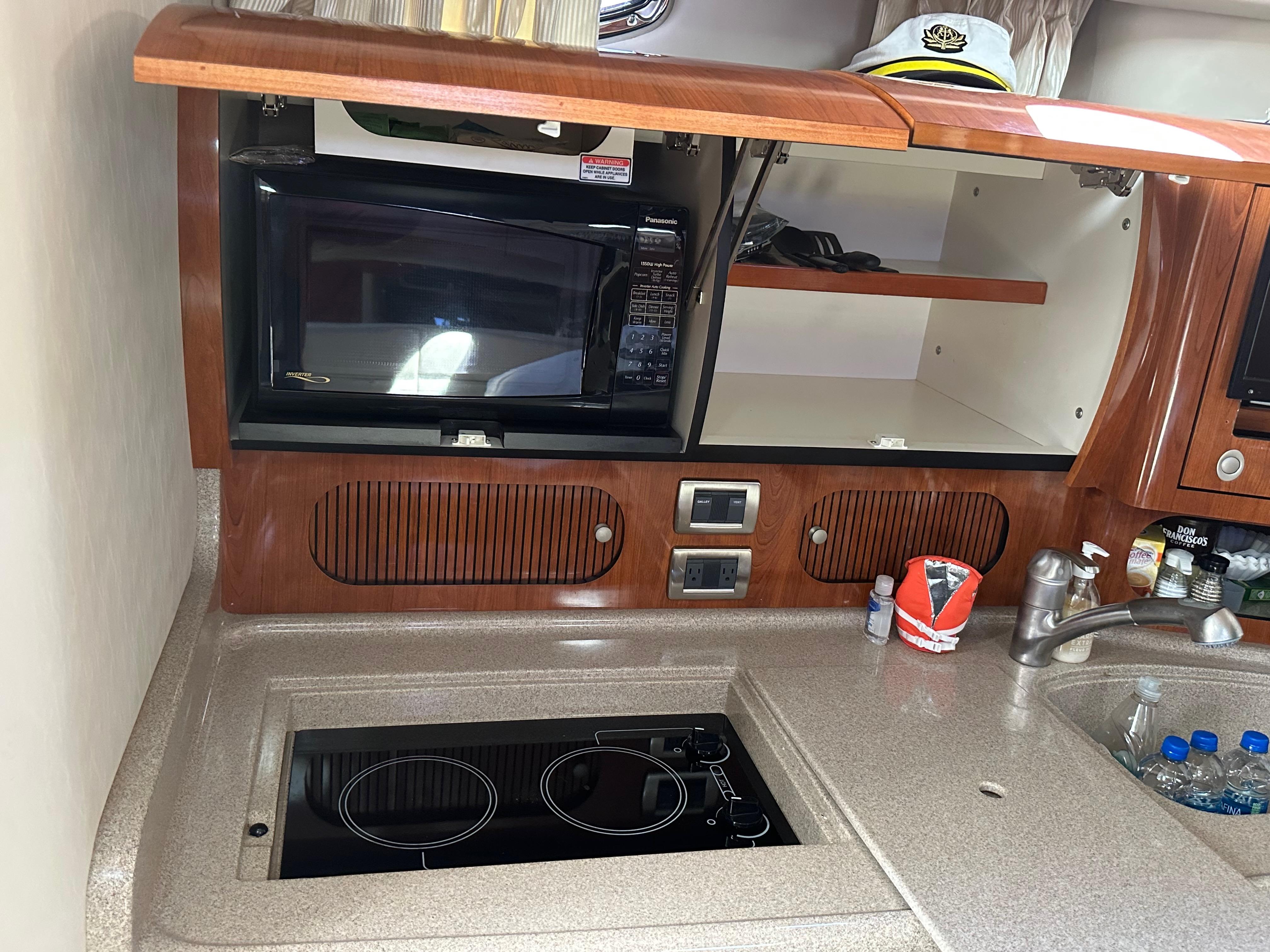 2004 Sea Ray 360 Sundancer kitchen with microwave, stove, and sink.