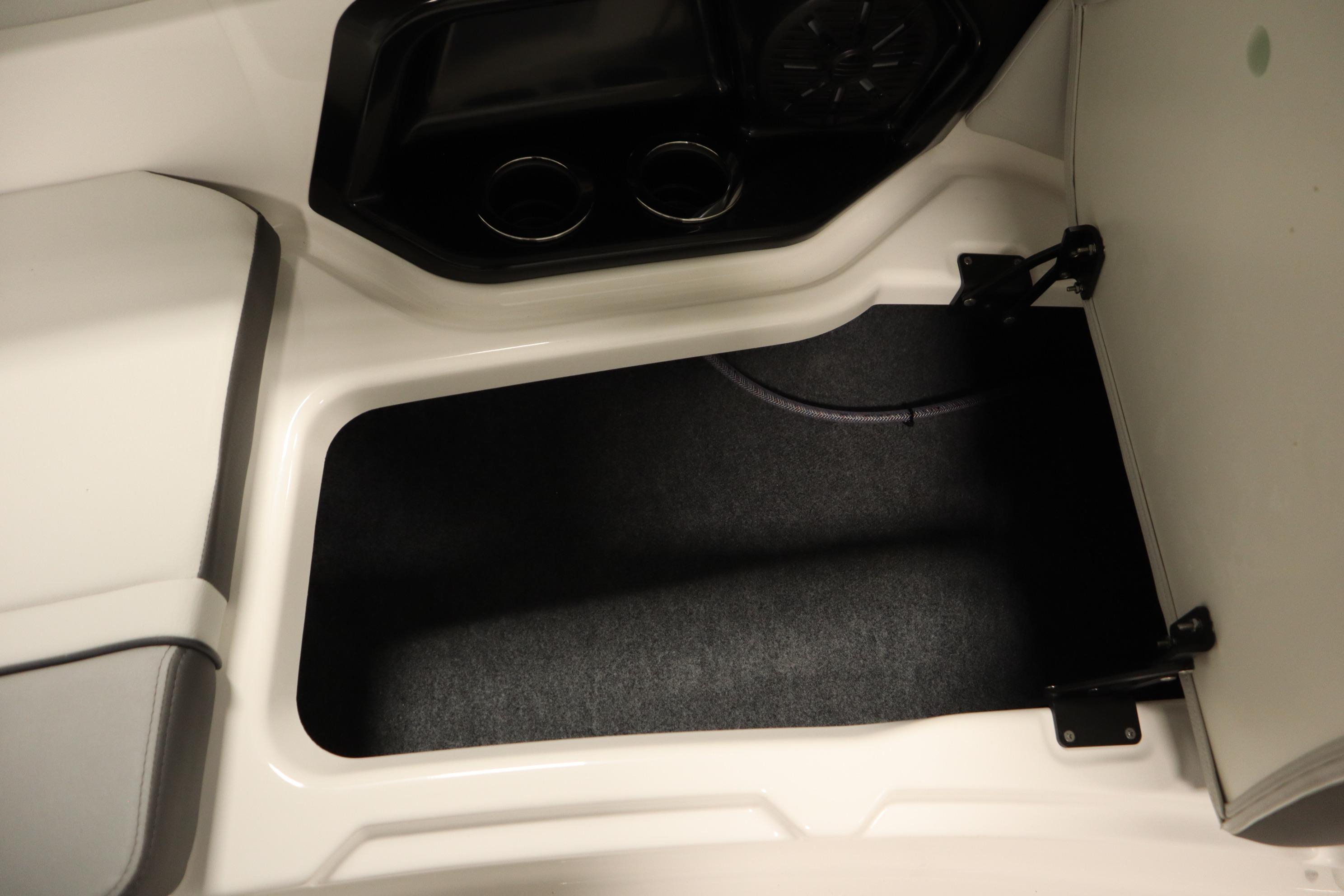 Interior storage compartment of 2026 Yamaha Boats AR250, featuring cup holders and speaker.