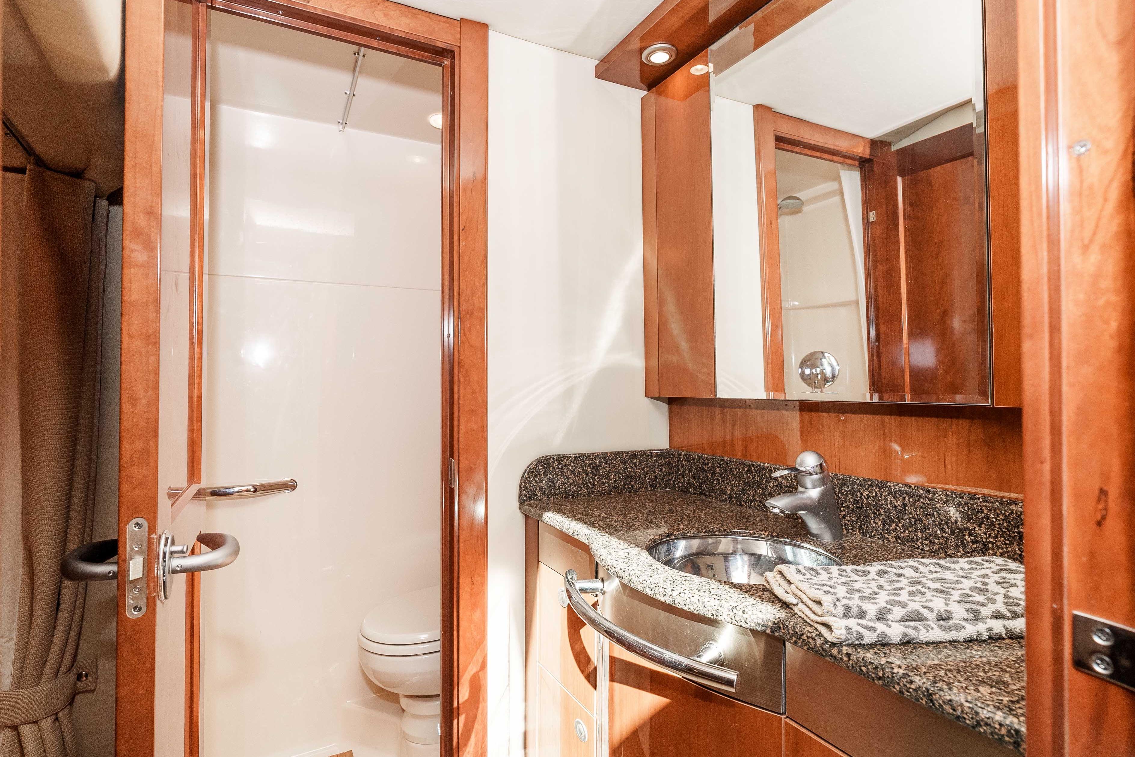 Luxurious bathroom in 2007 Sea Ray 48 Sundancer yacht with granite countertop and wooden cabinetry.