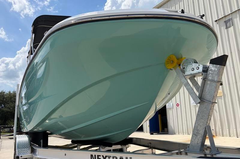 2026 Hurricane SunDeck Sport 2050 OB boat on trailer, light blue hull, sunny day.
