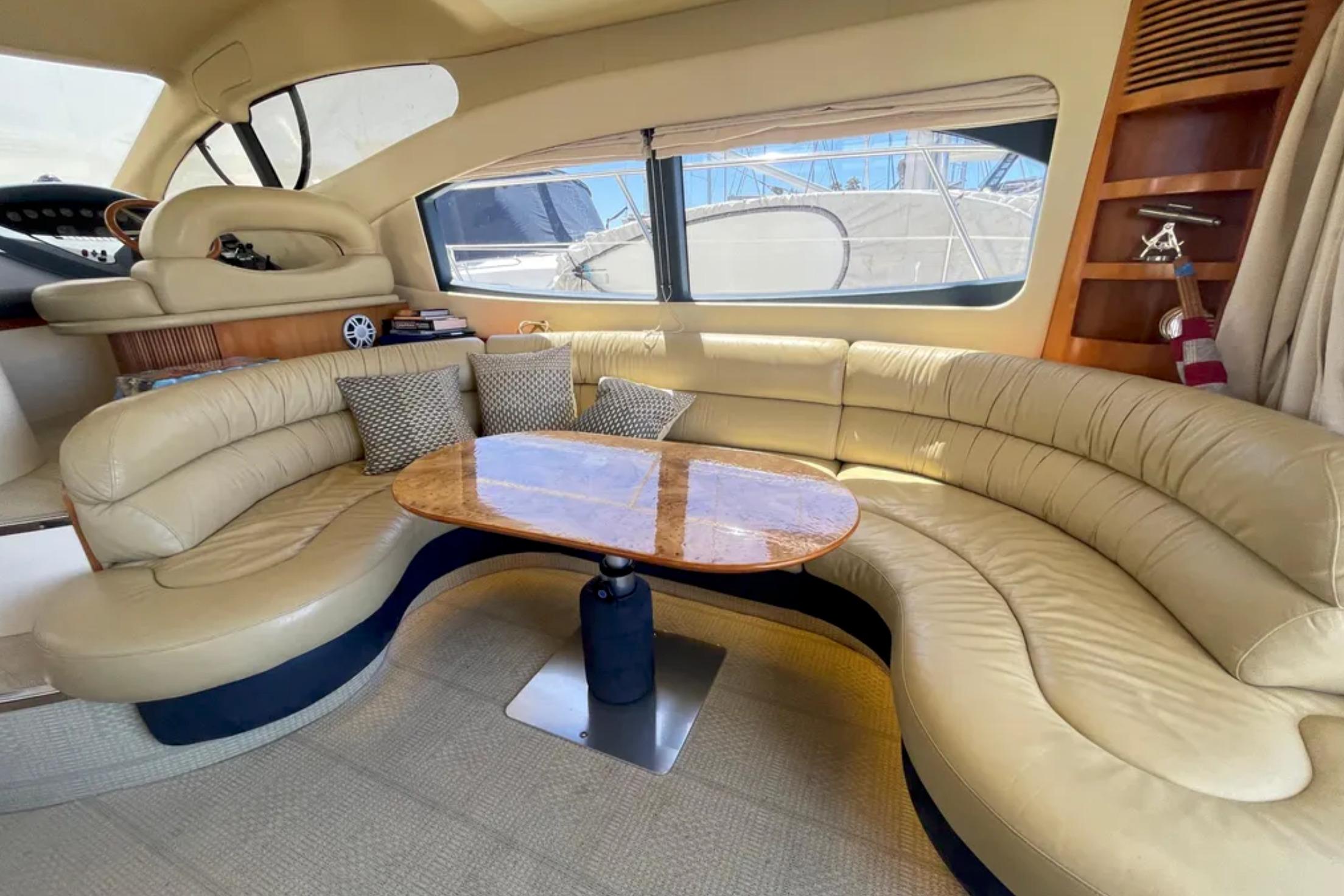 Luxurious interior of a 2004 Azimut 46 yacht with beige leather seating and wooden table.