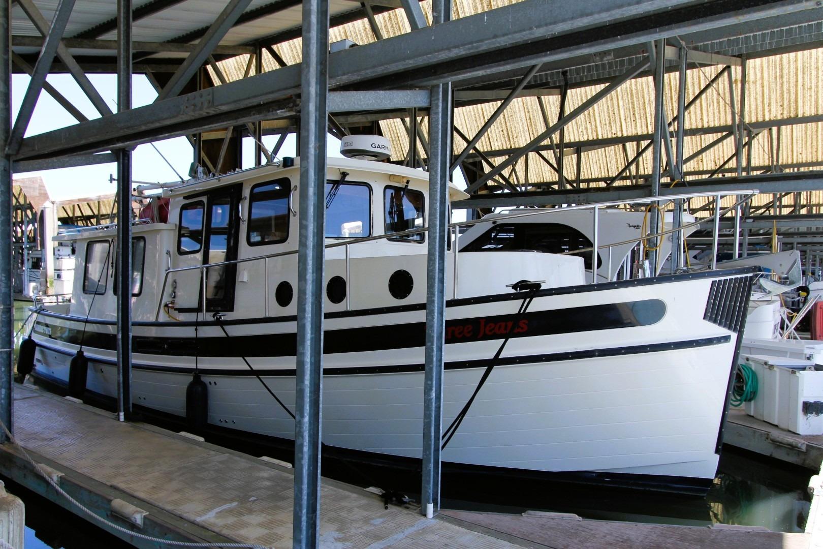 2002 Nordic Tug 37 docked in a covered marina, showcasing classic design.