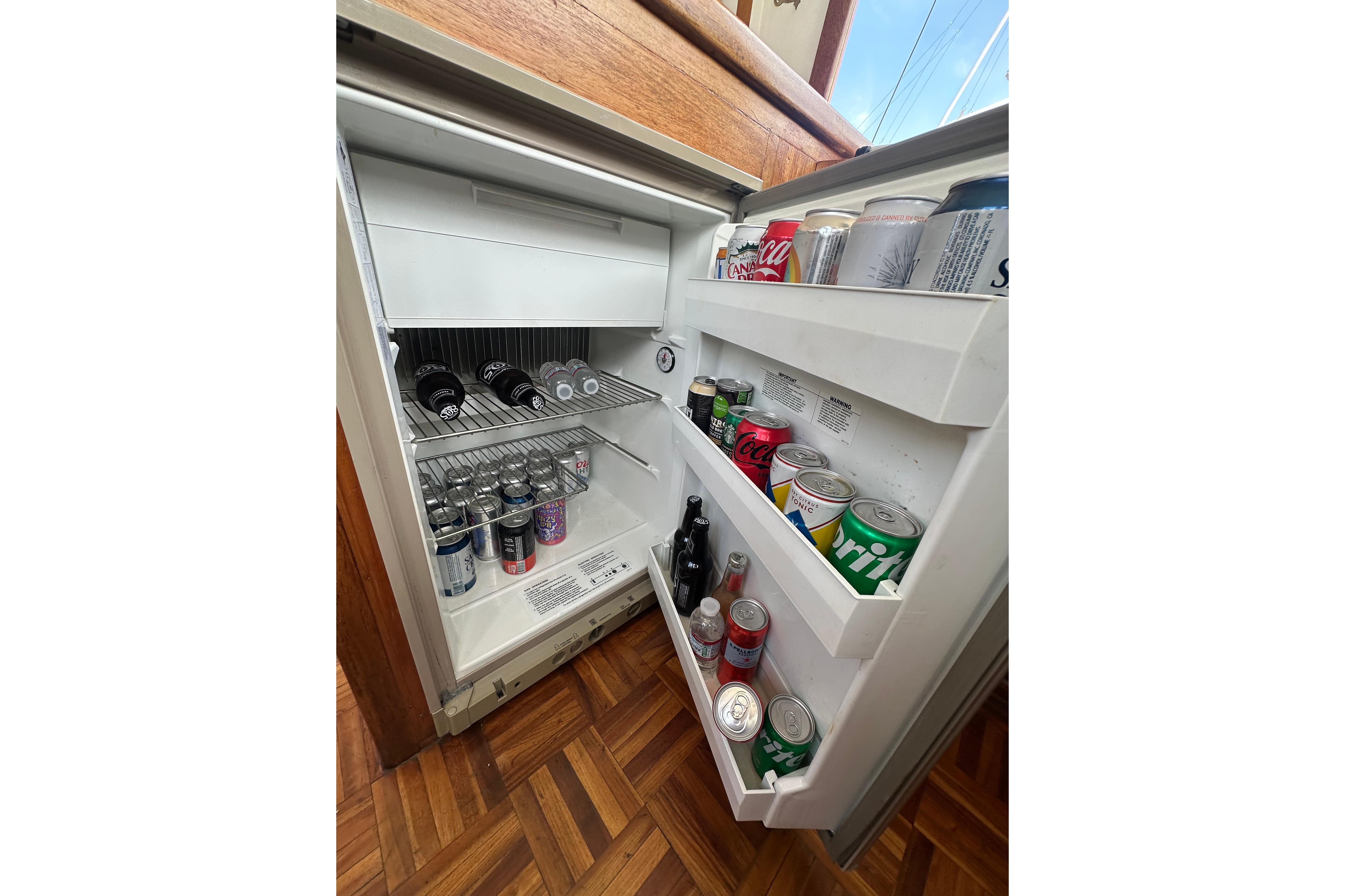 Open refrigerator stocked with various beverage cans and bottles on a CHB 33, 1973 model.