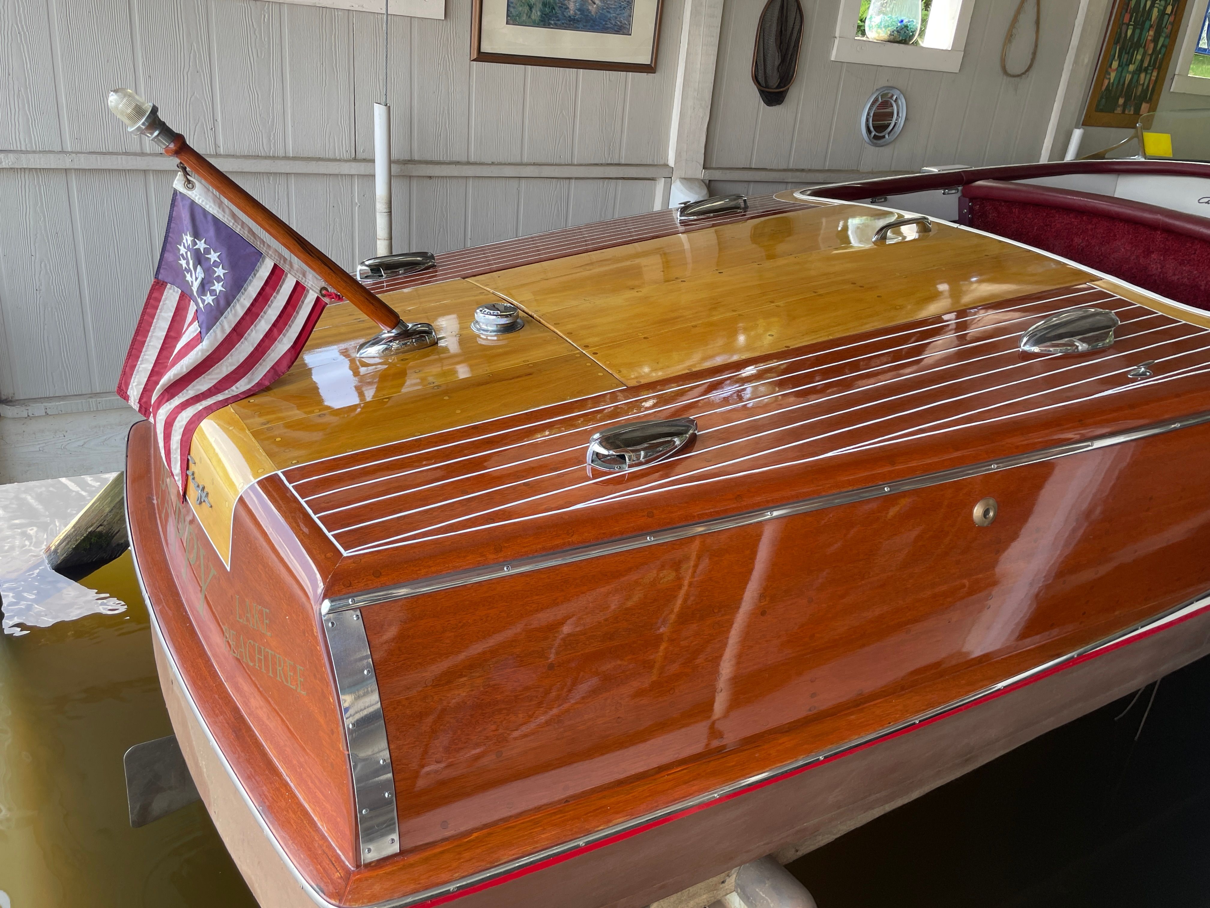 1954 Chris-Craft Riviera boat with polished wood and flag.
