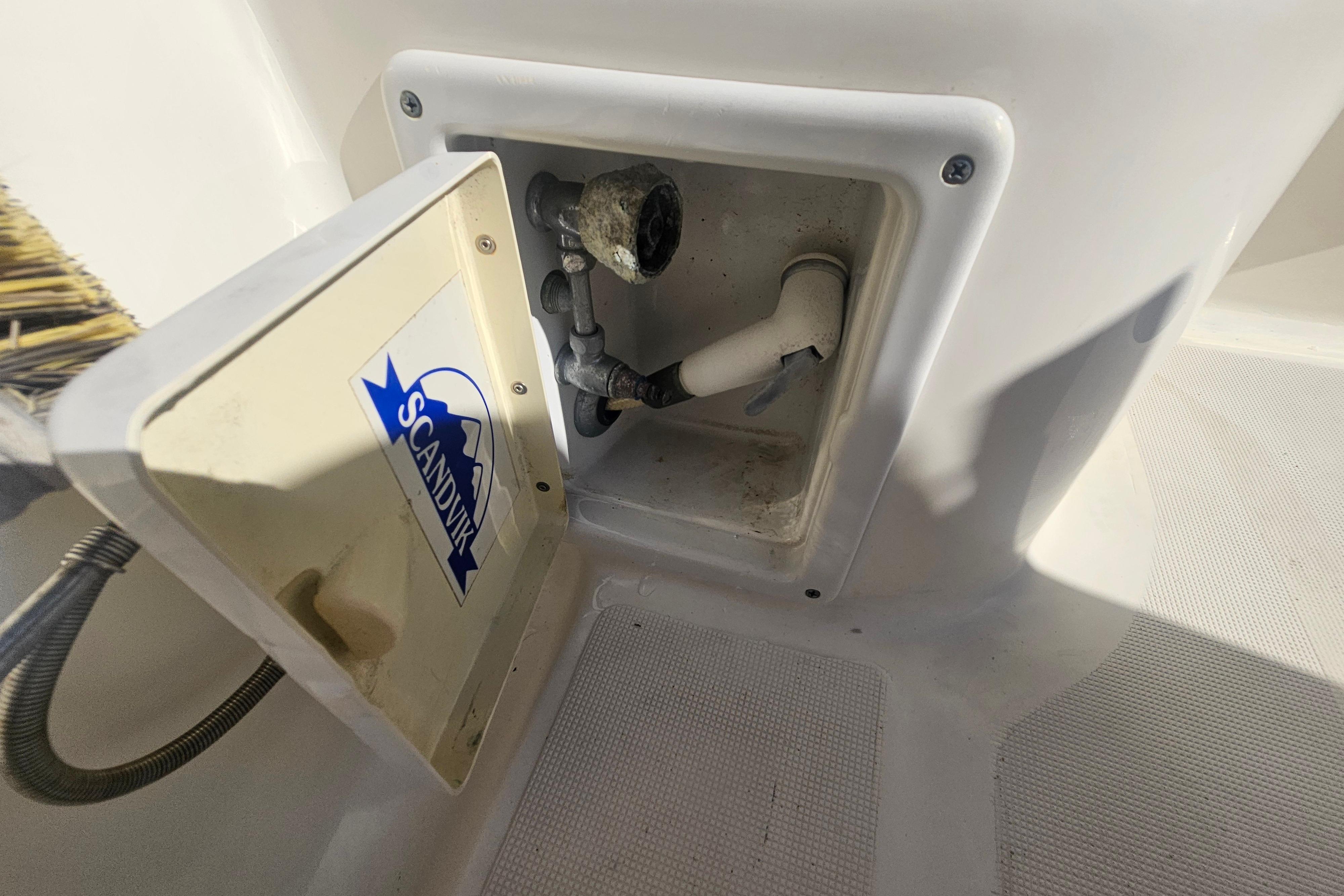 Open compartment on 2001 Pursuit 3000 Express boat with Scandvik label and plumbing components.