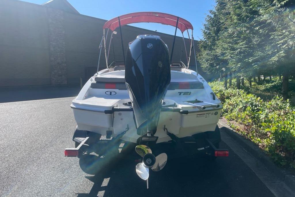 2026 Tahoe T21 boat with outboard motor, parked outdoors under sunlight.