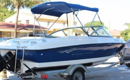A 2010 Bayliner 175 Bowrider on a trailer, featuring a blue canopy and white hull.