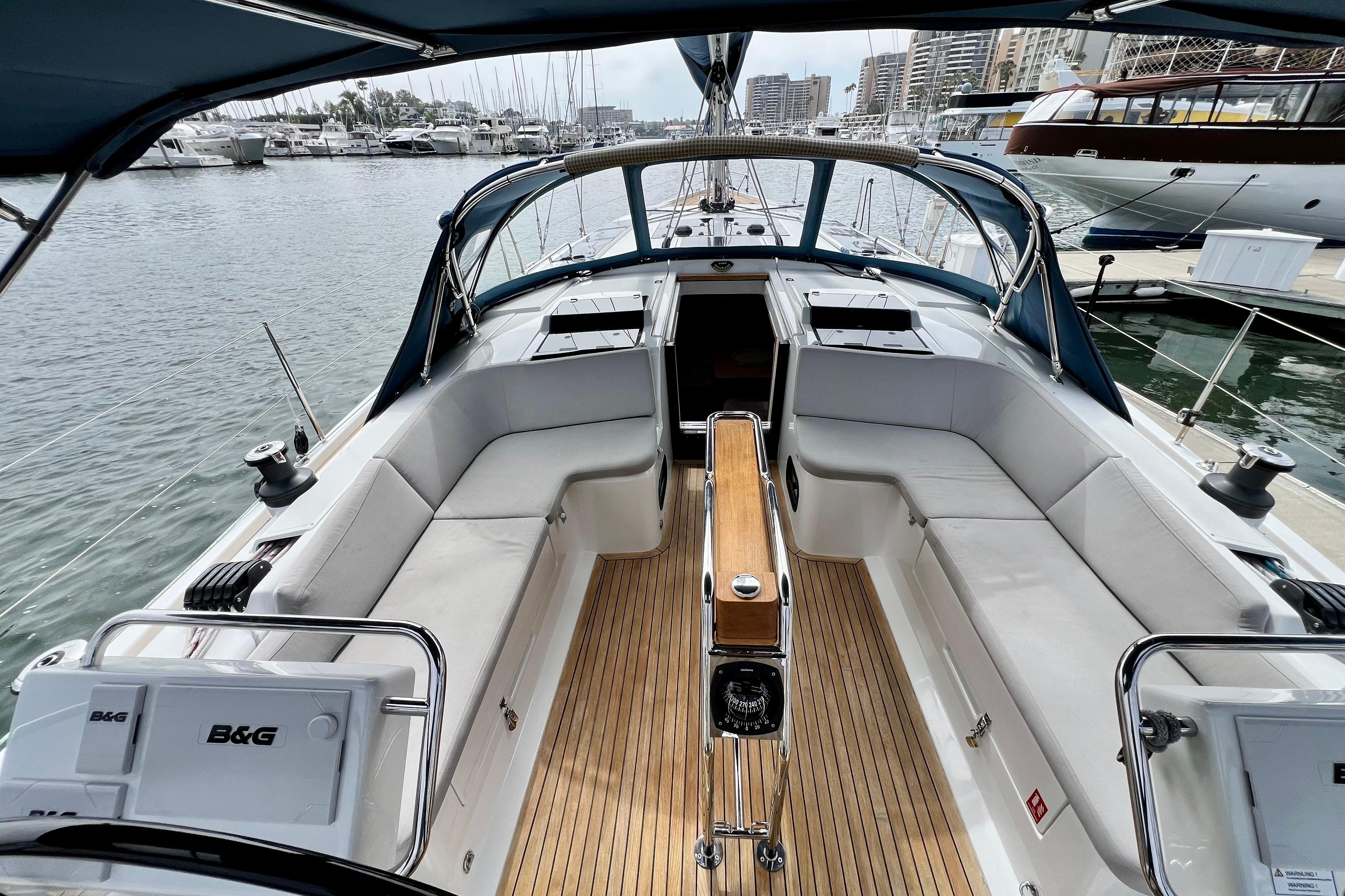 2016 Hanse 455 yacht cockpit with teak flooring, white seating, and marina view.