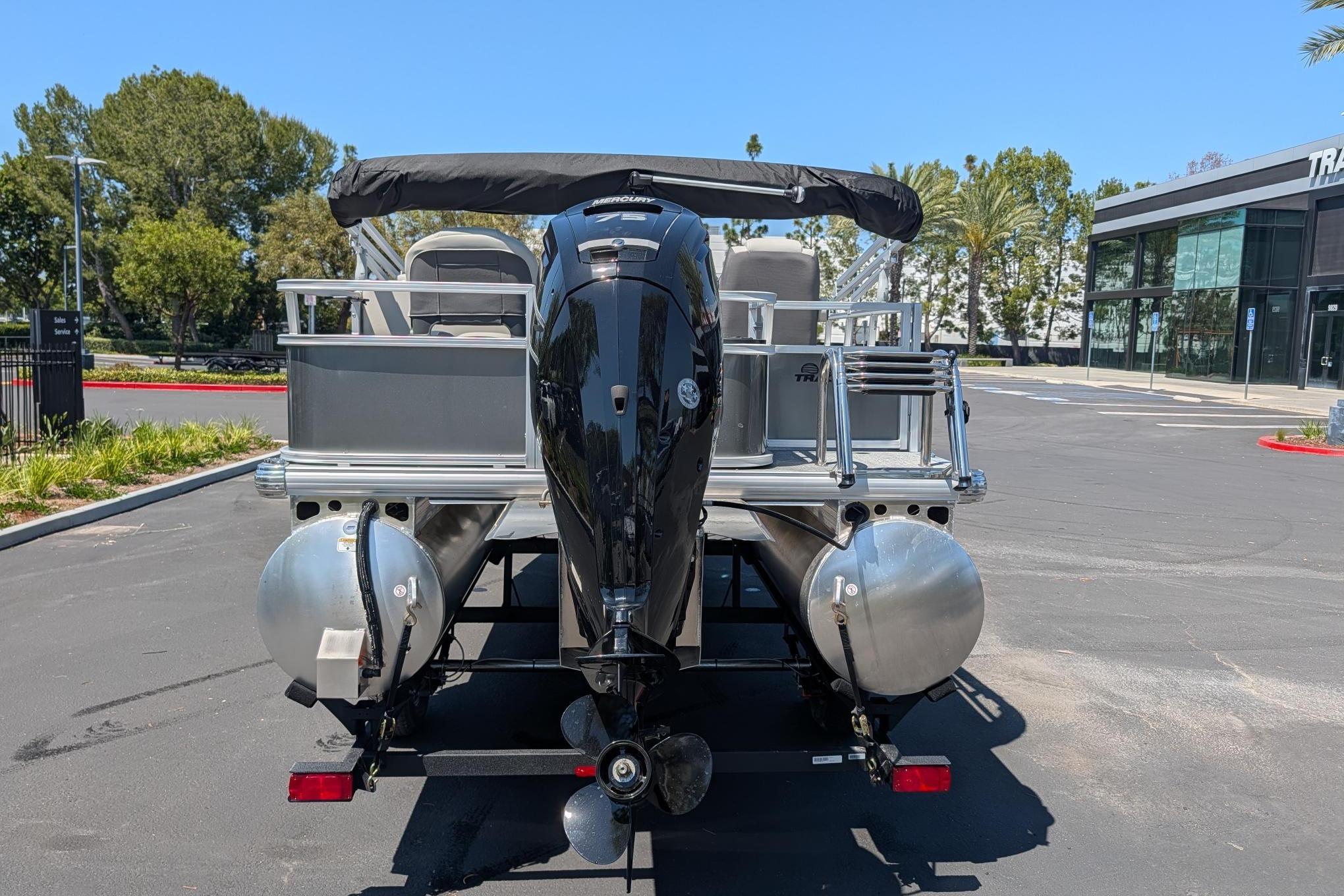 2026 Sun Tracker Bass Buggy 18 DLX pontoon boat with outboard motor, parked outdoors.