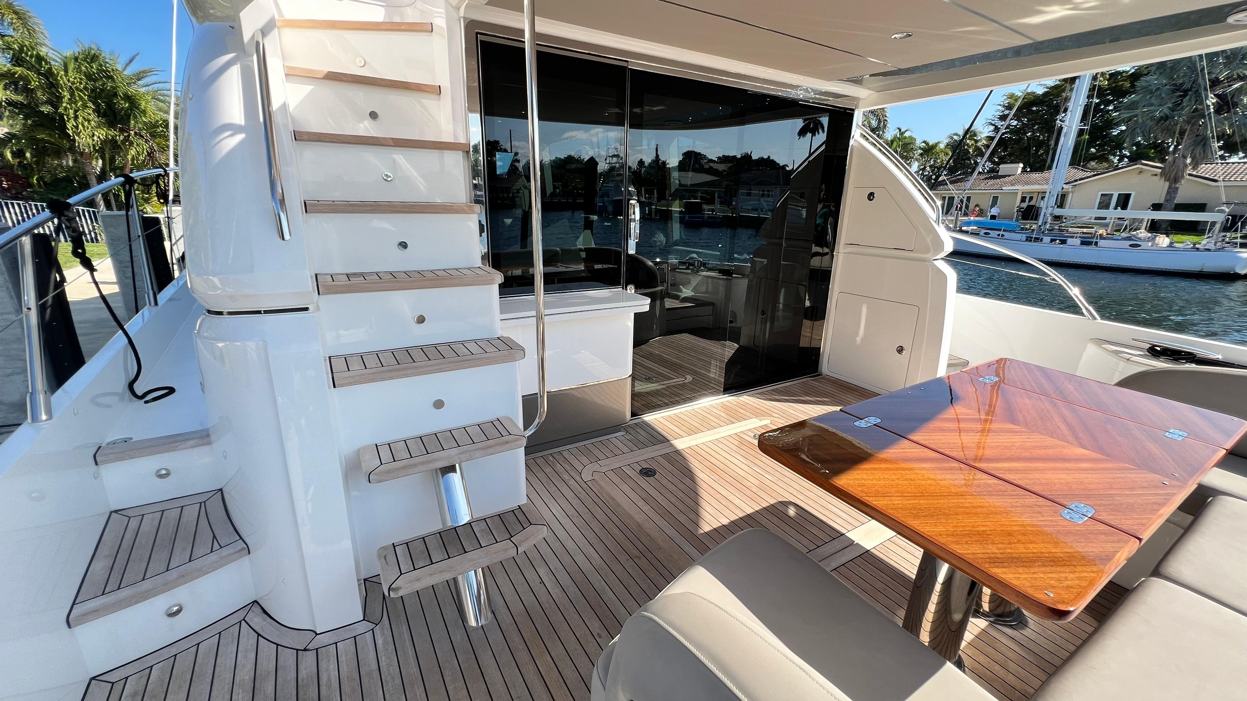 Luxurious 2019 Princess F62 yacht interior with wooden table and staircase, docked by the water.