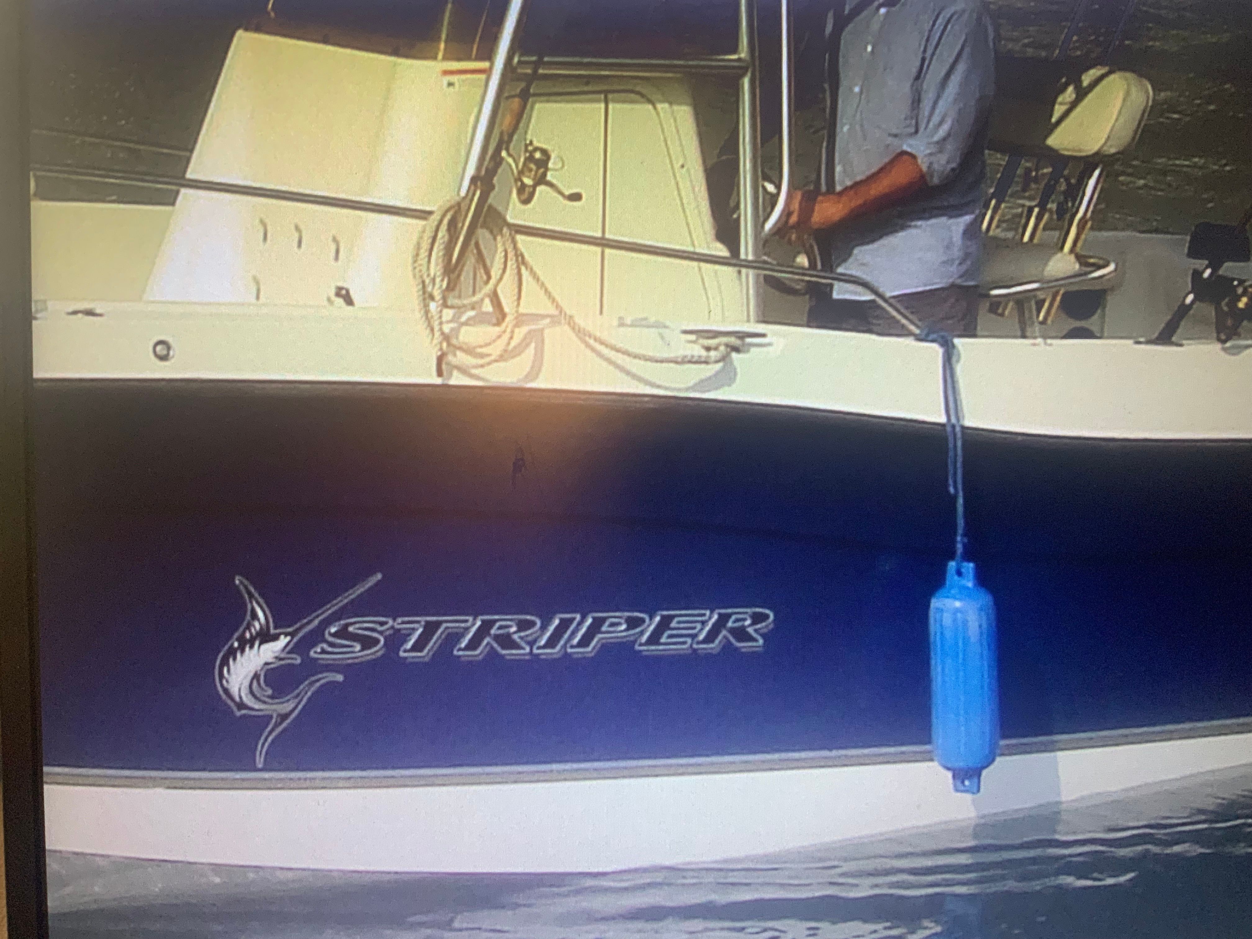 A 2006 Seaswirl Striper 26 boat with a blue hull and fender, on the water.