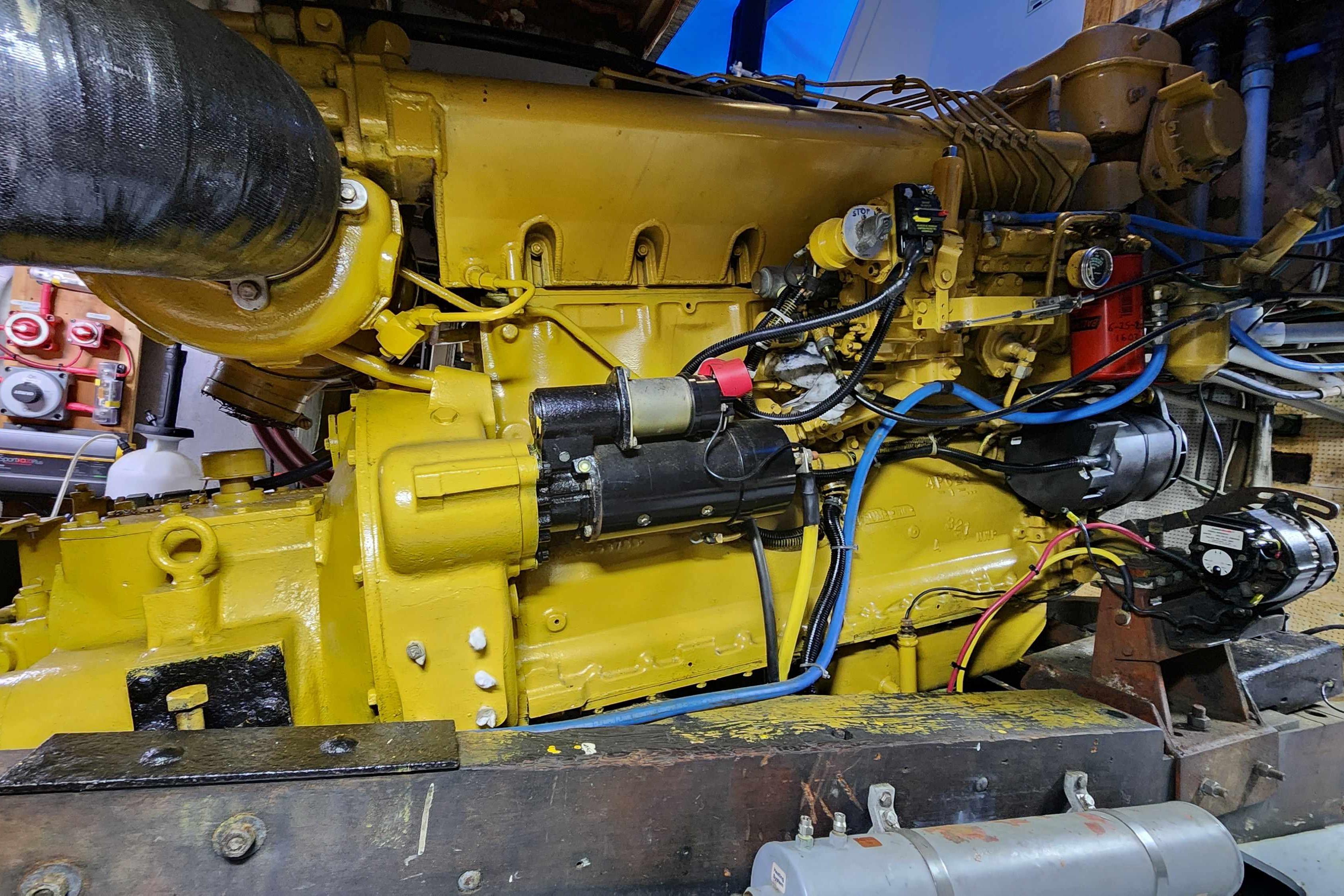 Yellow engine of a 1964 Grandy Tour Boat, showcasing intricate mechanical components.