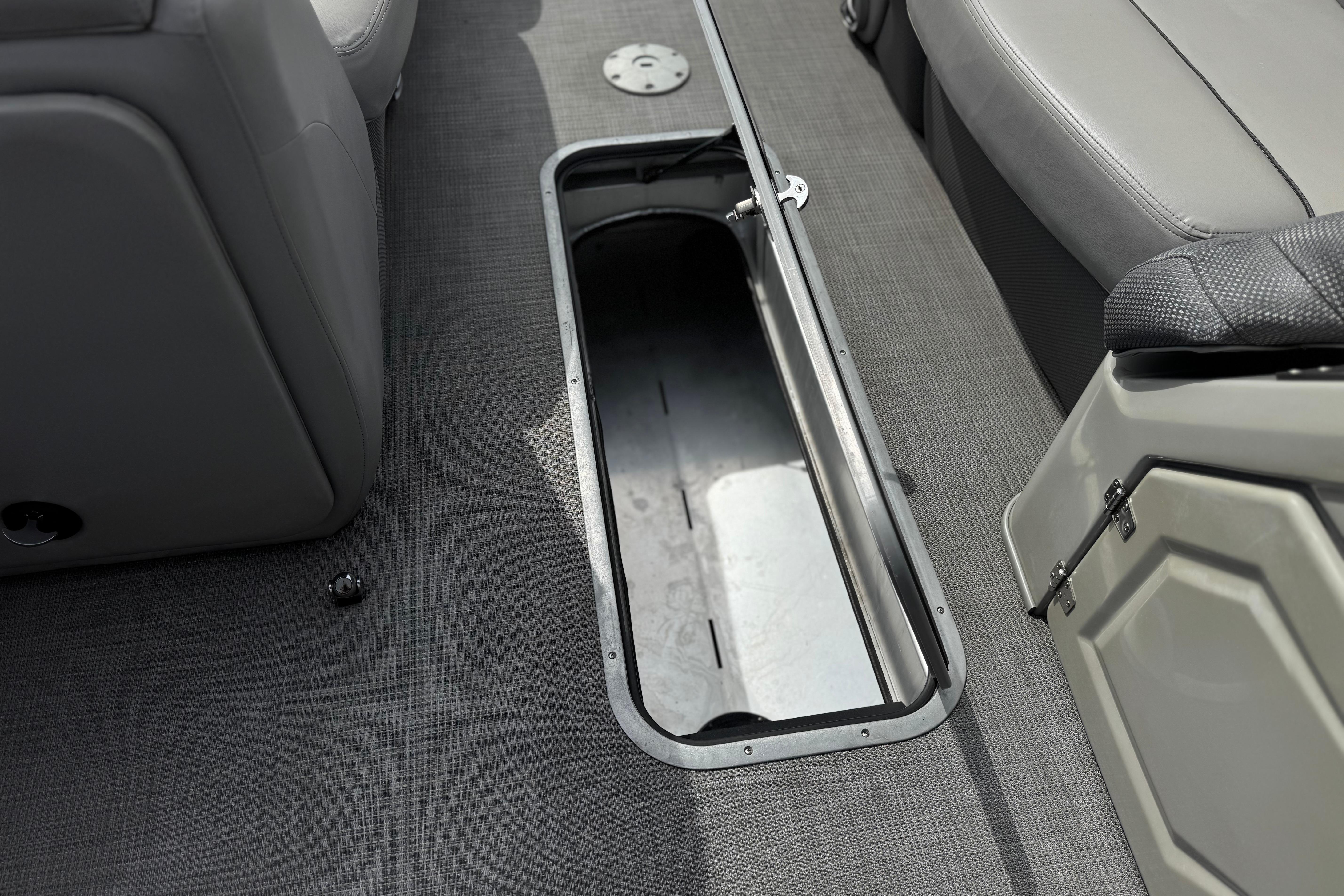 Open storage compartment on 2022 Regency 250 DL3 boat with gray seating and flooring.