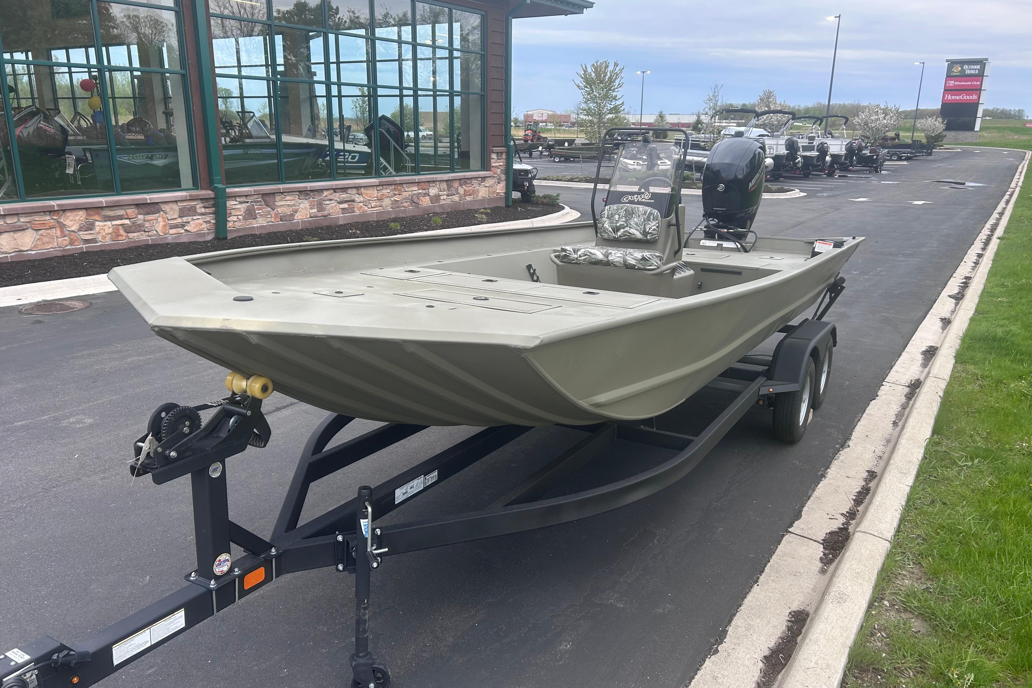 2024 Tracker Grizzly 2072 CC boat on trailer, parked outside a building.