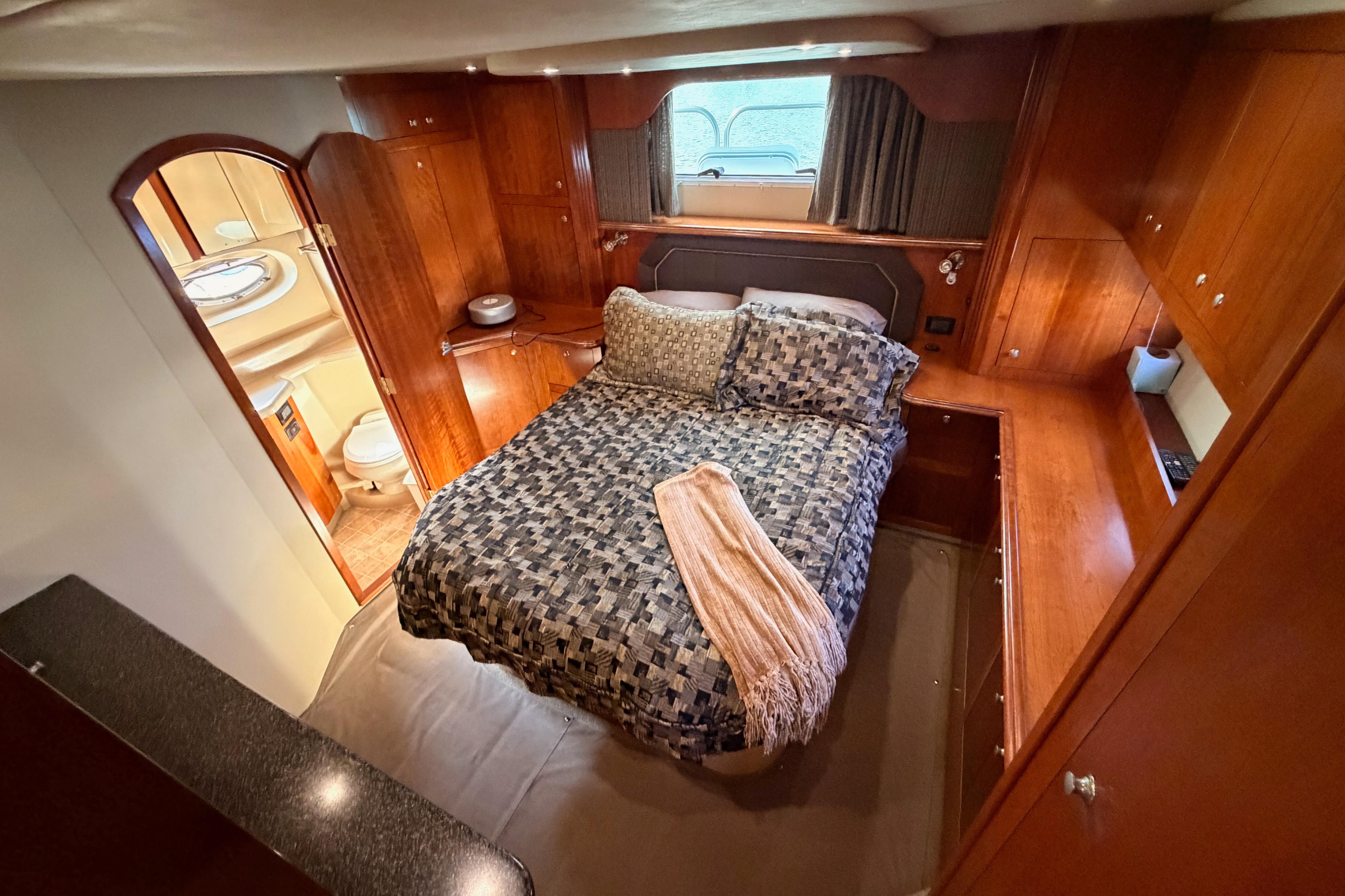 Luxurious bedroom in 2005 Cruisers Yachts 405 Express Motoryacht with elegant wood cabinetry.