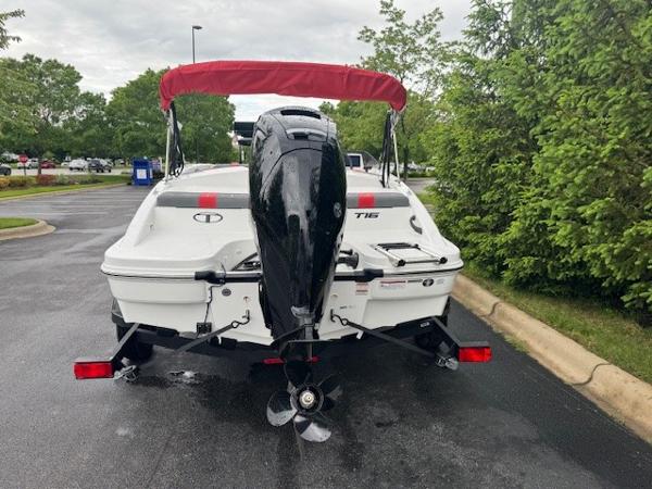 2025 Tahoe T16 boat with red canopy on a trailer, parked on a wet road.
