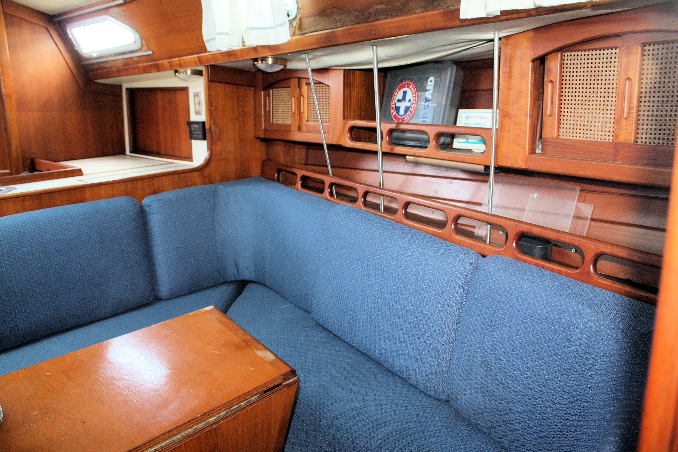 Interior of 1987 Ericson 38-200 sailboat with blue seating and wooden cabinetry.