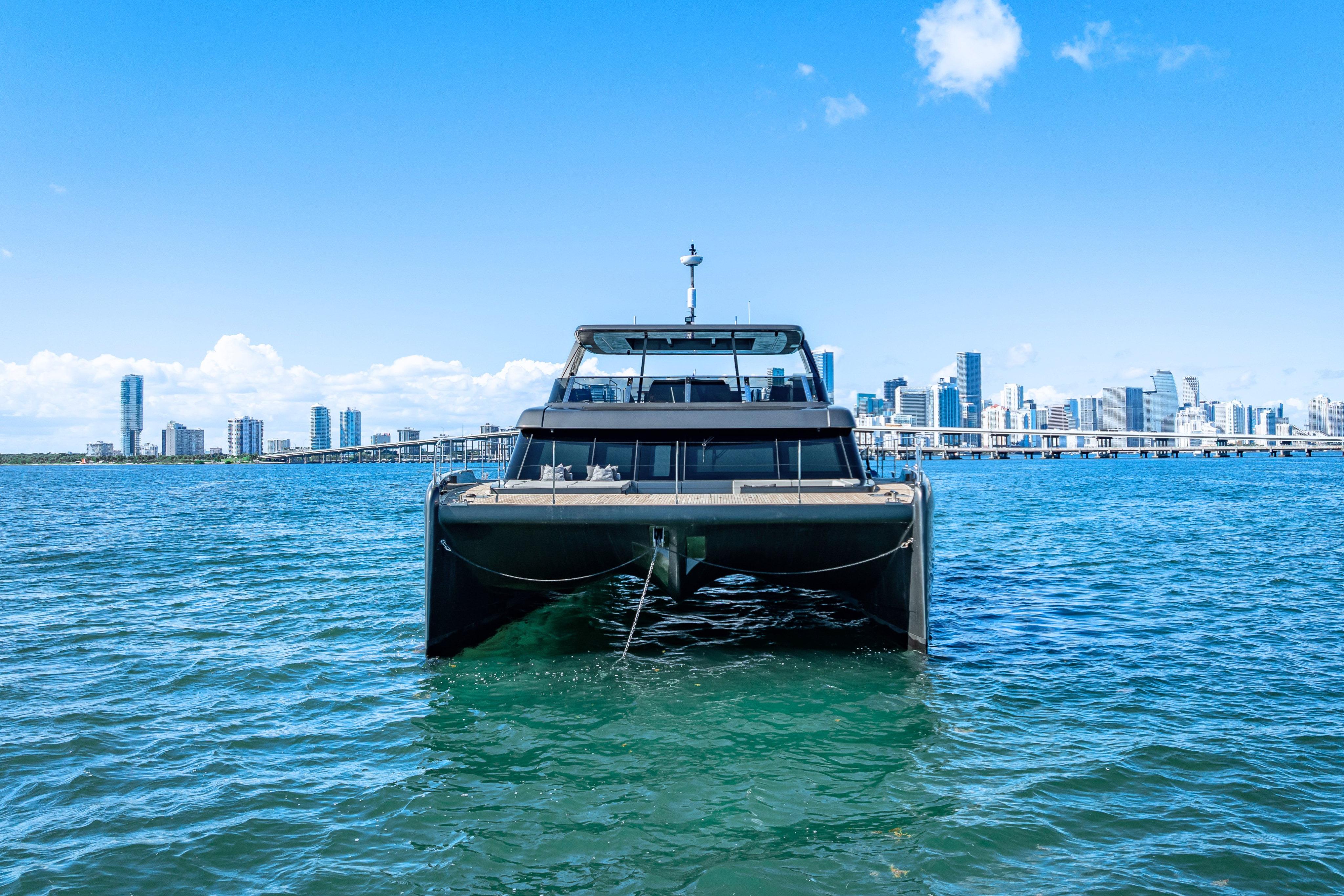 2026 Sunreef 60 Power yacht on blue water with city skyline backdrop.