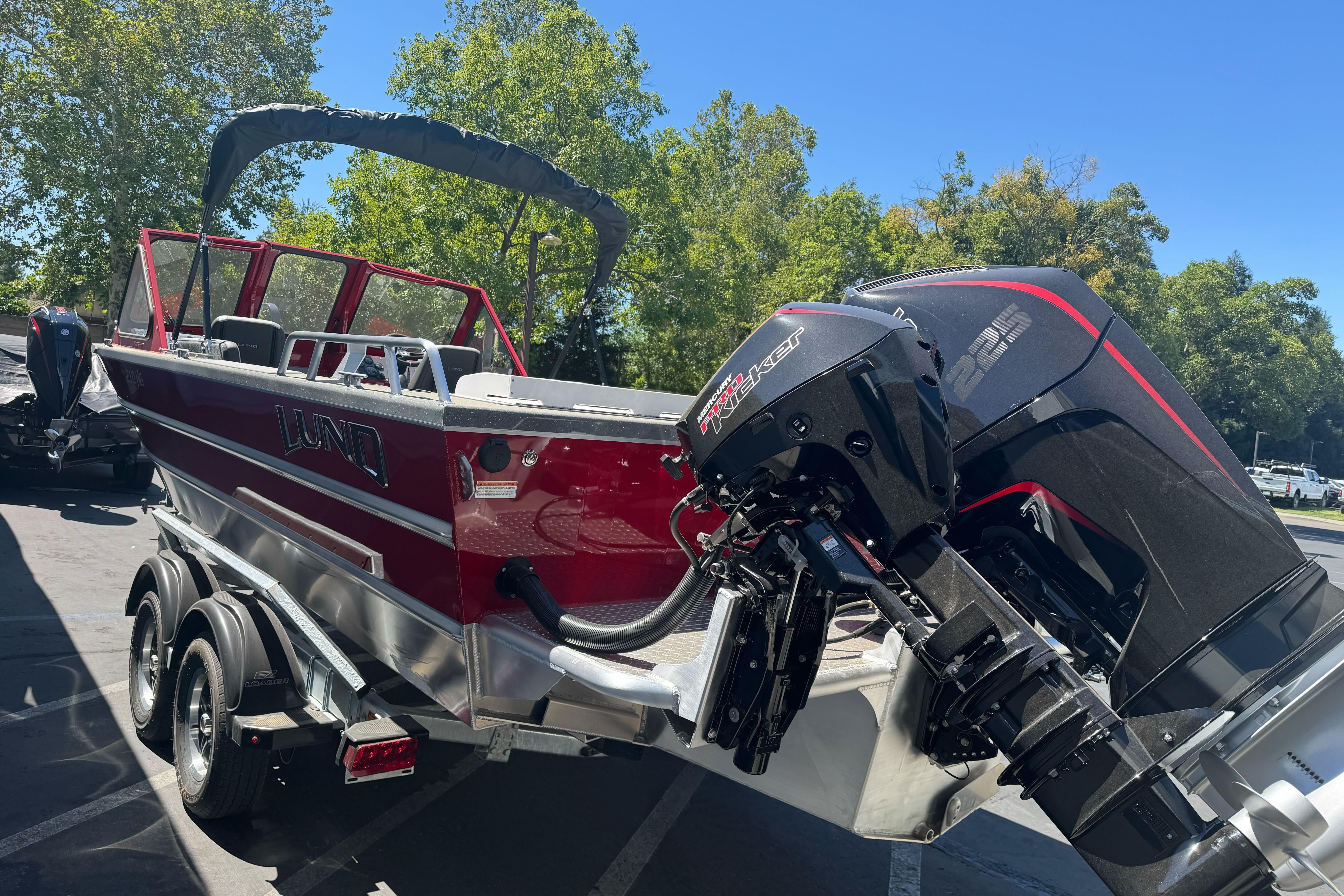2026 Lund 210 Heavy Gauge boat with powerful outboard motor, parked outdoors.