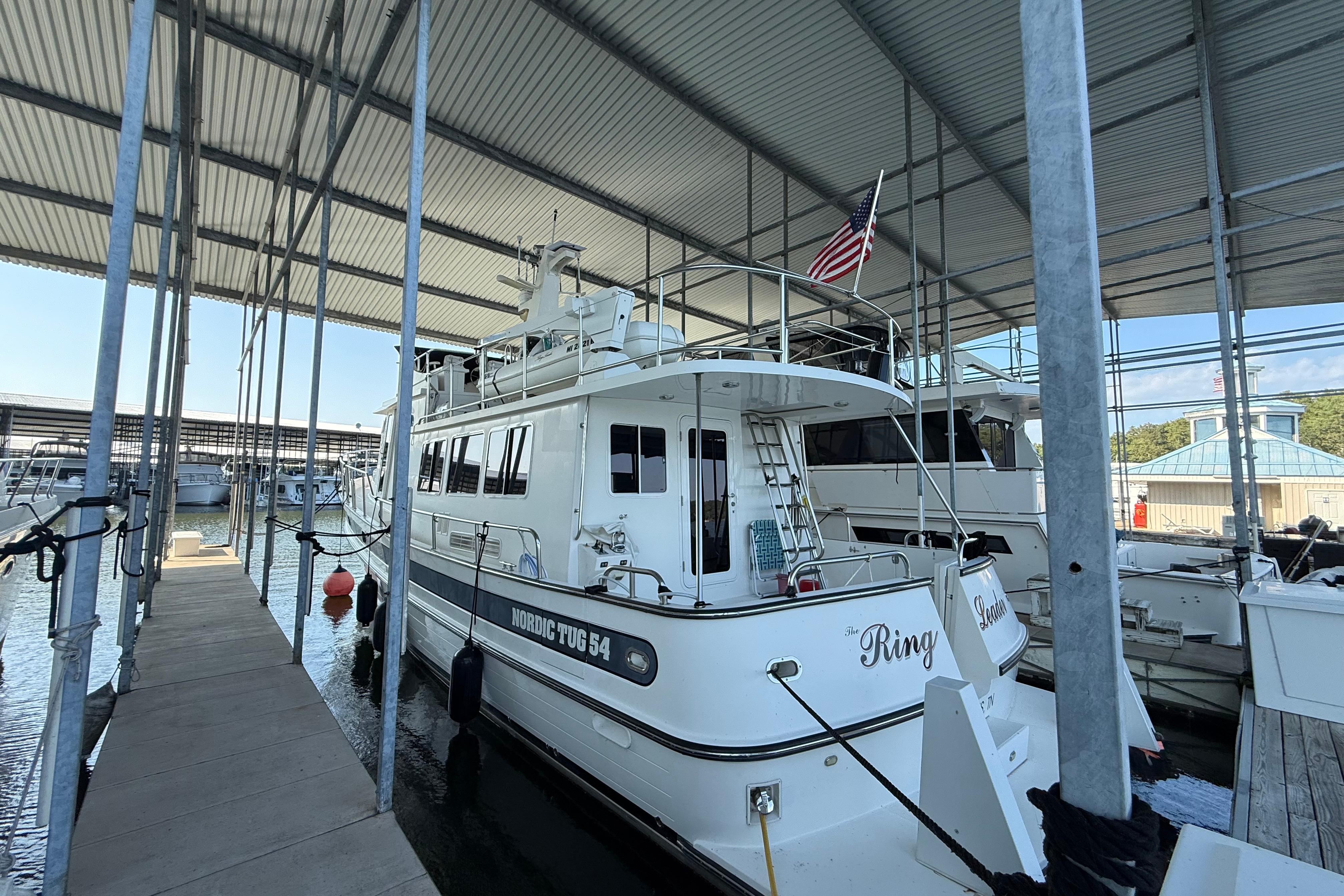 2007 Nordic Tug 54 docked under covered marina with American flag.