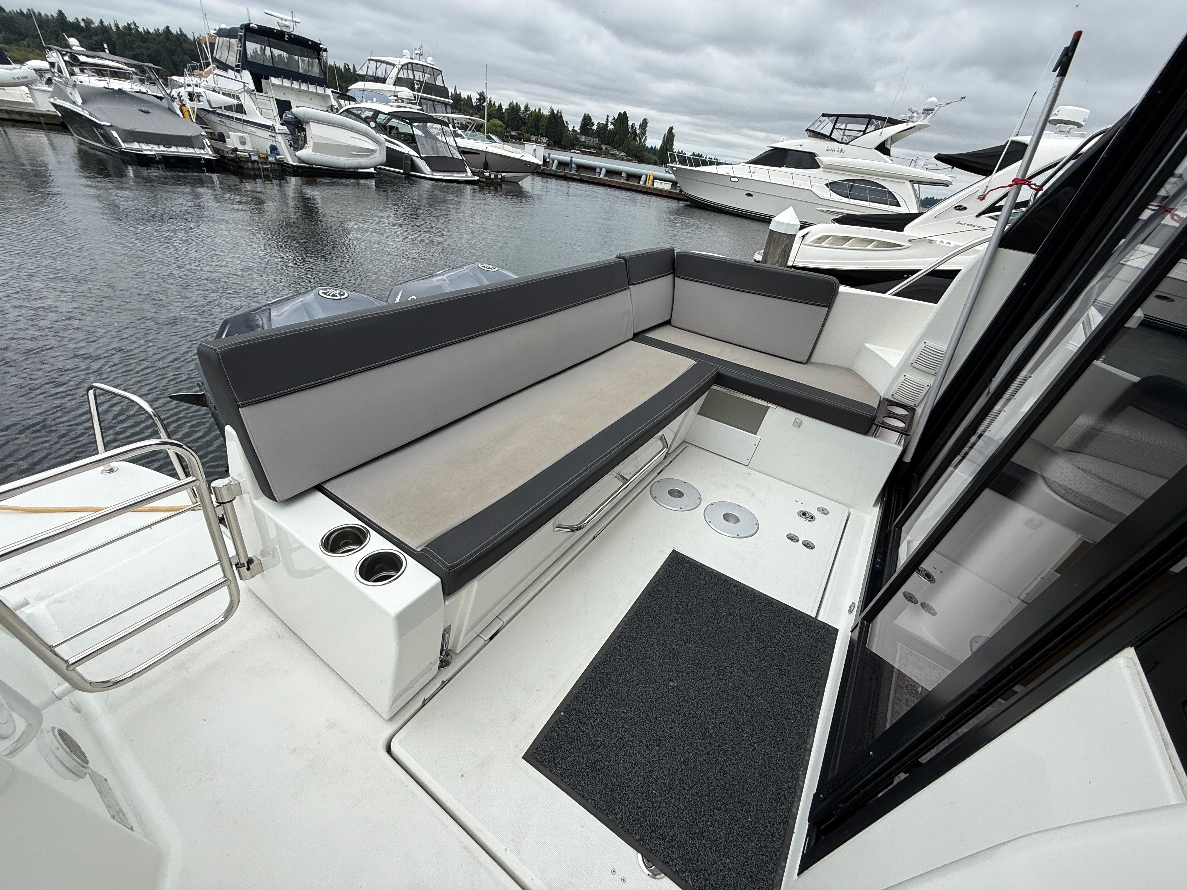 The image shows the stern of a 2021 Jeanneau NC 1095 with gray seating cushions.
